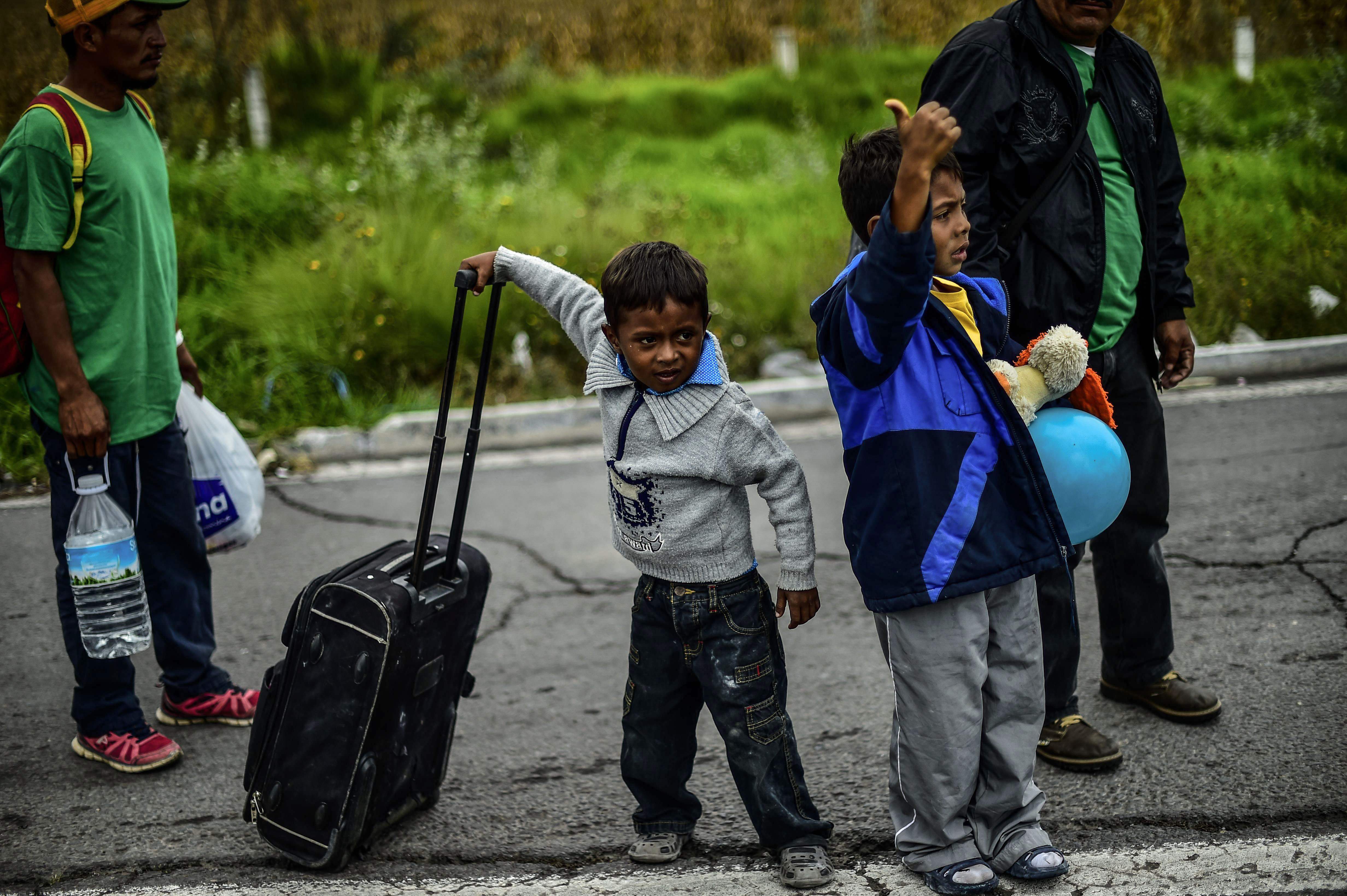 Migrant children on a caravan of mostly Hondurans, moving towards the United States in hopes of a better life or to escape violence, hitchhike alongside the Mexico City-Puebla highway in San Matias Tlalancaleca, Puebla state, Mexico, on November 5, 2018. - US President Donald Trump has ordered regular army troops to the US-Mexican border as a caravan of a few thousand impoverished migrants slowly marches toward the boundary. (Photo by PEDRO PARDO / AFP)