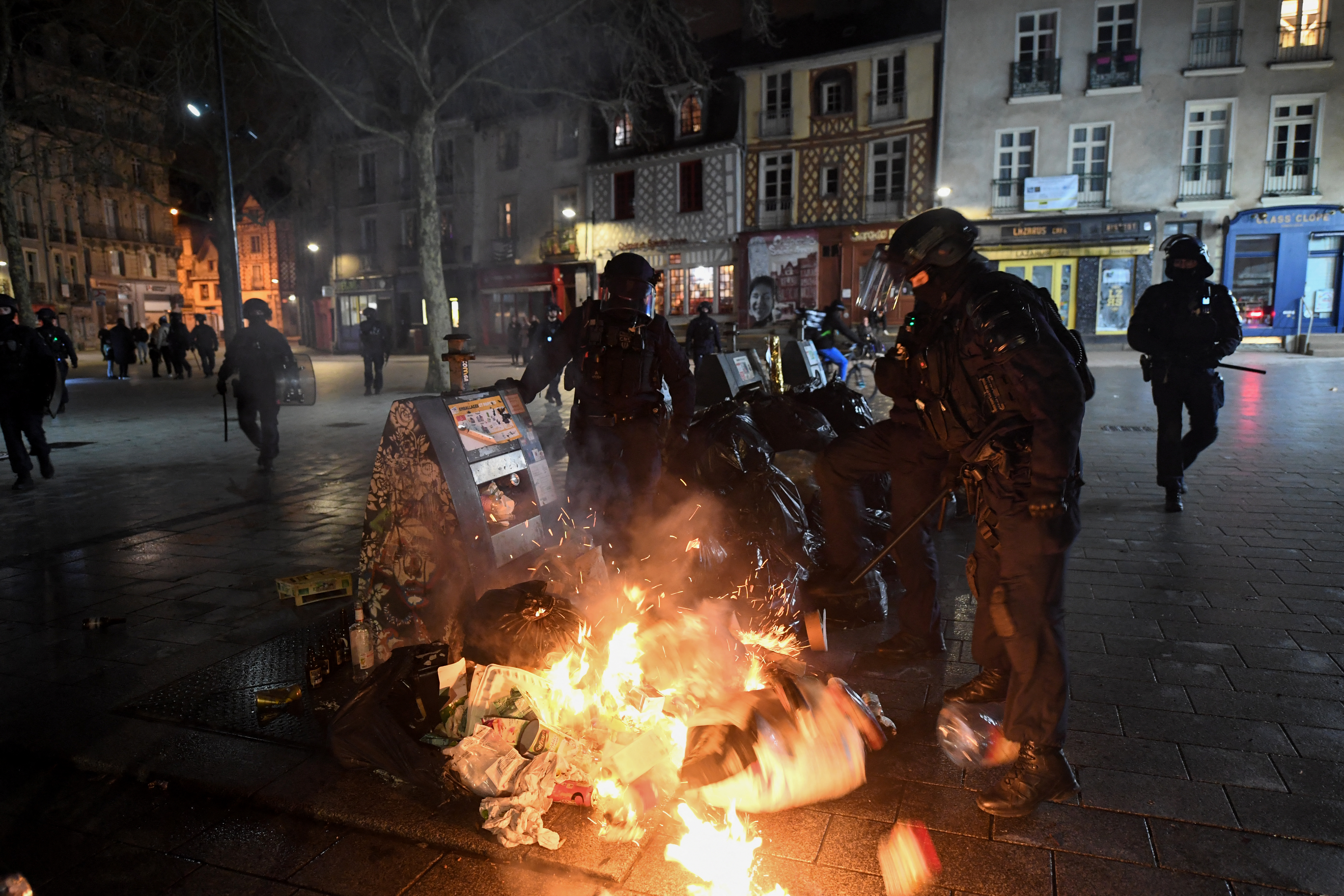 French CRS (Compagnie Republicaine de Securite or Republican Security Corps) Police extinguish rubbish set on fire during protests in Rennes, western France, on March 18, 2023, two days after the French government imposed a pension reform using article 49,3 of the constitution. - Opponents of France's President's pension reform plan to express their anger over the weekend, with new rallies and strikes in France, which is plunged into a political crisis after the executive's power grab. (Photo by JEAN-FRANCOIS MONIER / AFP)