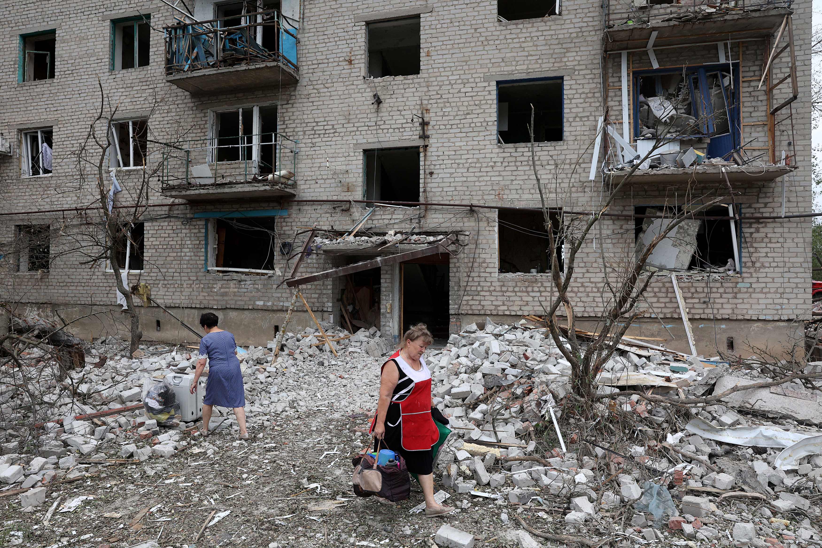 TOPSHOT - A local resident woman carries her belongings out of a building partially destroyed following shelling in Chasiv Yar, eastern Ukraine, on July 10, 2022. - The four-story building was hit by a Russian Hurricane missile, Pavlo Kyrylenko, governor of the Donetsk region that the Russian army is seeking to conquer, said on July 10, 2022 on Telegram. (Photo by Anatolii Stepanov / AFP)