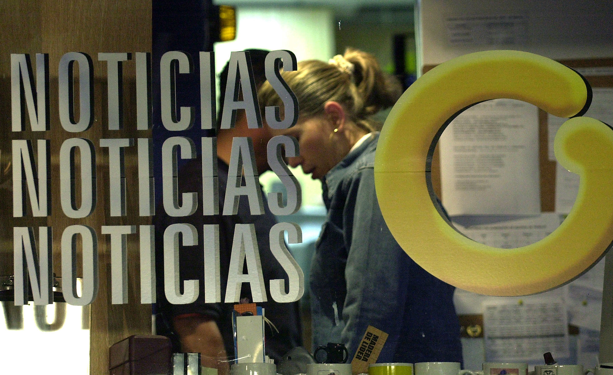FILE - In this Oct. 3, 2003 file photo, an employee at Globovision, a 24-hour television news channel, works behind a glass reading "News" with Globovision's logo "G" at the channel's headquarters in Caracas, Venezuela. On Jan. 8, 2019, the Trump administration is imposing sanctions on Venezuelan media magnate Raul Gorrin for allegedly running a network that stole $2.4 billion from state coffers through corrupt currency deals, giving Gorrin one year to divest his shares in Globovision. (AP Photo/Leslie Mazoch, File)