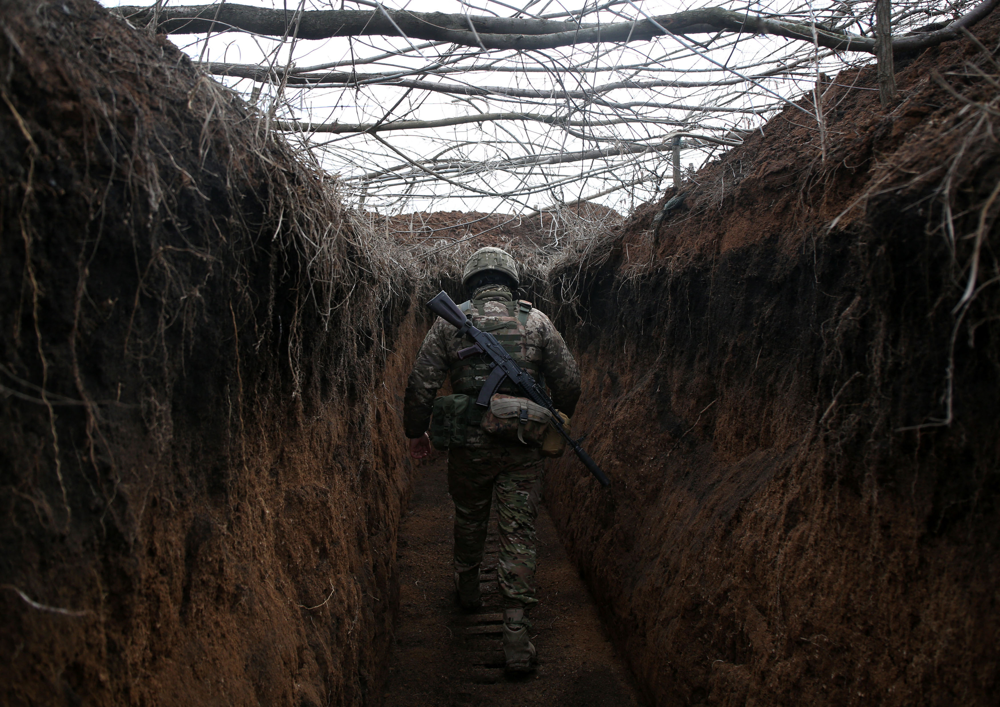 A serviceman of Ukrainian Military Forces walks along trench on his position on the front line with Russia backed separatists not far Novolugansk, Donetsk region on February 16, 2022. (Photo by Anatolii STEPANOV / AFP)