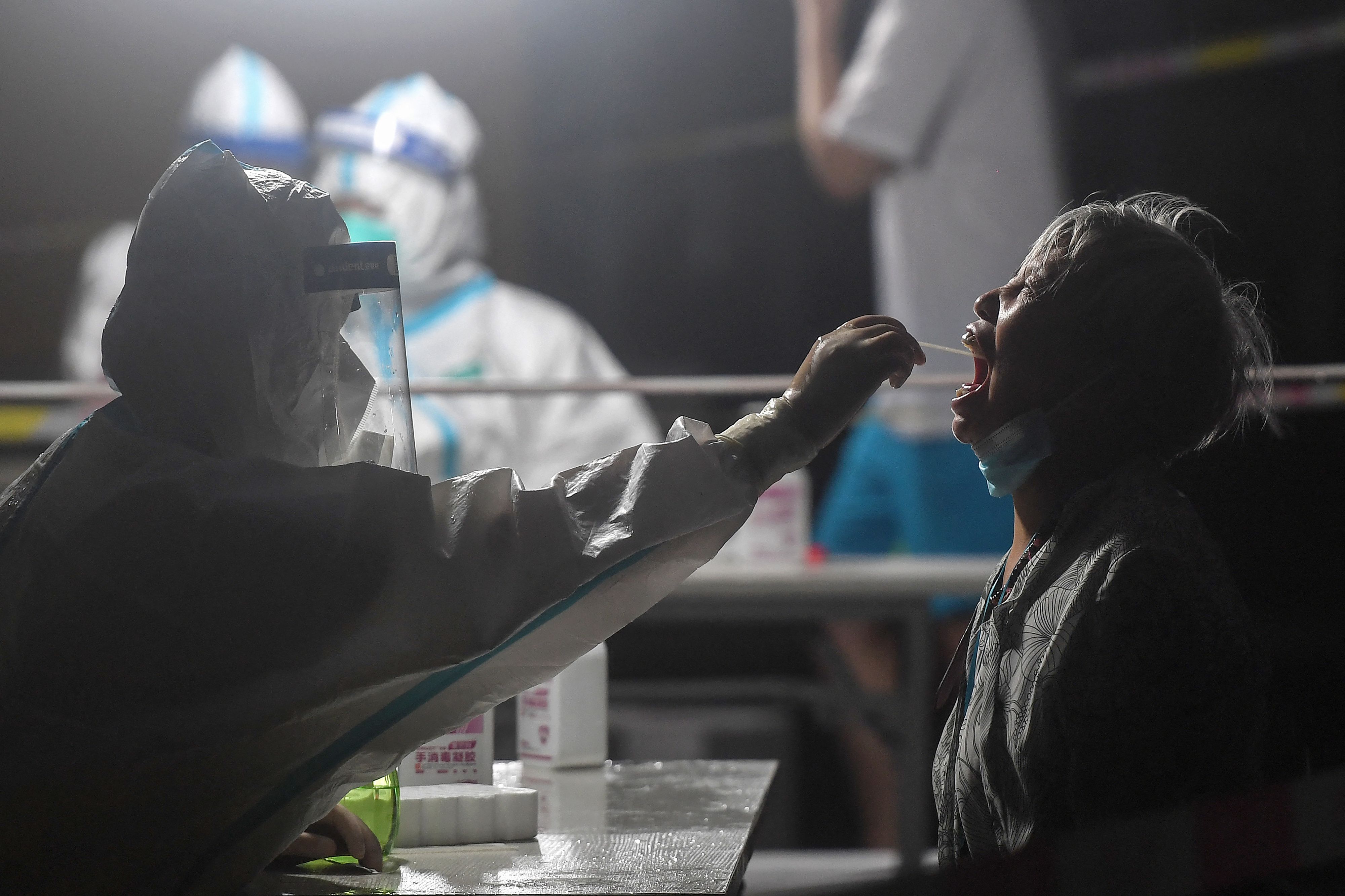 This photo taken on August 11, 2021 shows a resident receiving a nucleic acid test for the Covid-19 coronavirus at a residental area which is restricted due to the virus in Wuhan, in China's central Hubei province. (Photo by STR / AFP) / China OUT