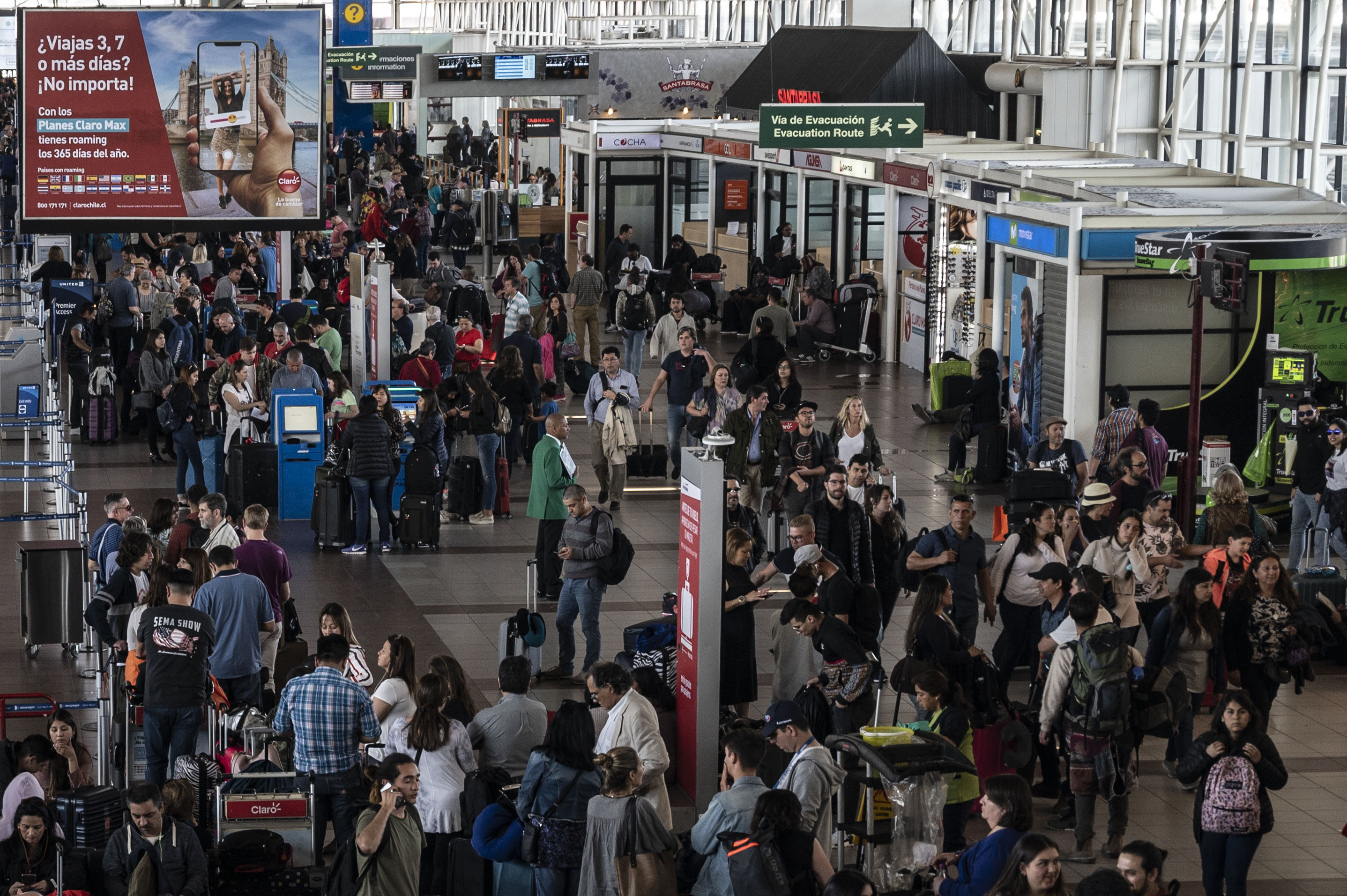People wait inside the international airport in Santiago on October 20, 2019. Almost all public transport in the capital of seven million people was paralyzed on Sunday, with shops shuttered and many flights in and out of Santiago's international airport cancelled. After an emergency meeting with top state officials late Sunday, President Sebastian Pinera defended his decision to call a state of emergency -- announced Friday -- and deploy thousands of troops onto the streets. (Photo by Pedro UGARTE / AFP)