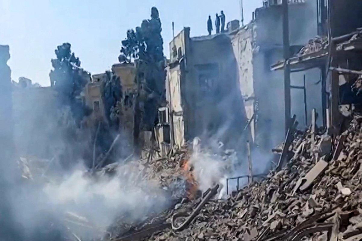 Este fotograma de un video obtenido de imágenes de usuarios publicadas en redes sociales el 28 de febrero de 2026 y verificado por equipos de AFPTV en París muestra a personas inspeccionando los daños en un punto de impacto tras ataques de Estados Unidos e Israel contra Teherán.