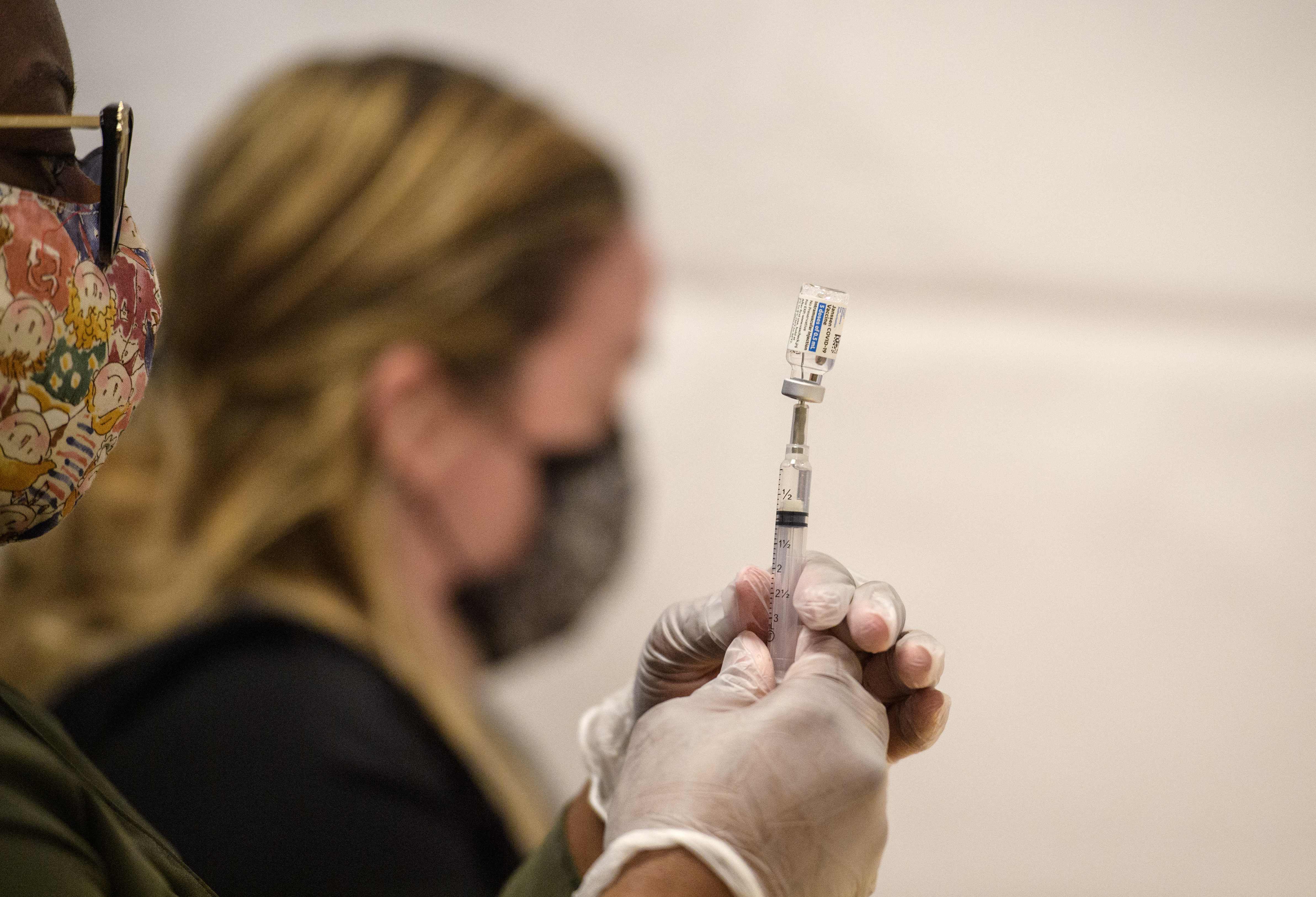 Healthcare workers prepare a syringe with a vial of the J&J/Janssen Covid-19 vaccine at a temporary vaccination site at Grand Central Terminal train station on May 12, 202 in New York City. (Photo by Angela Weiss / AFP)