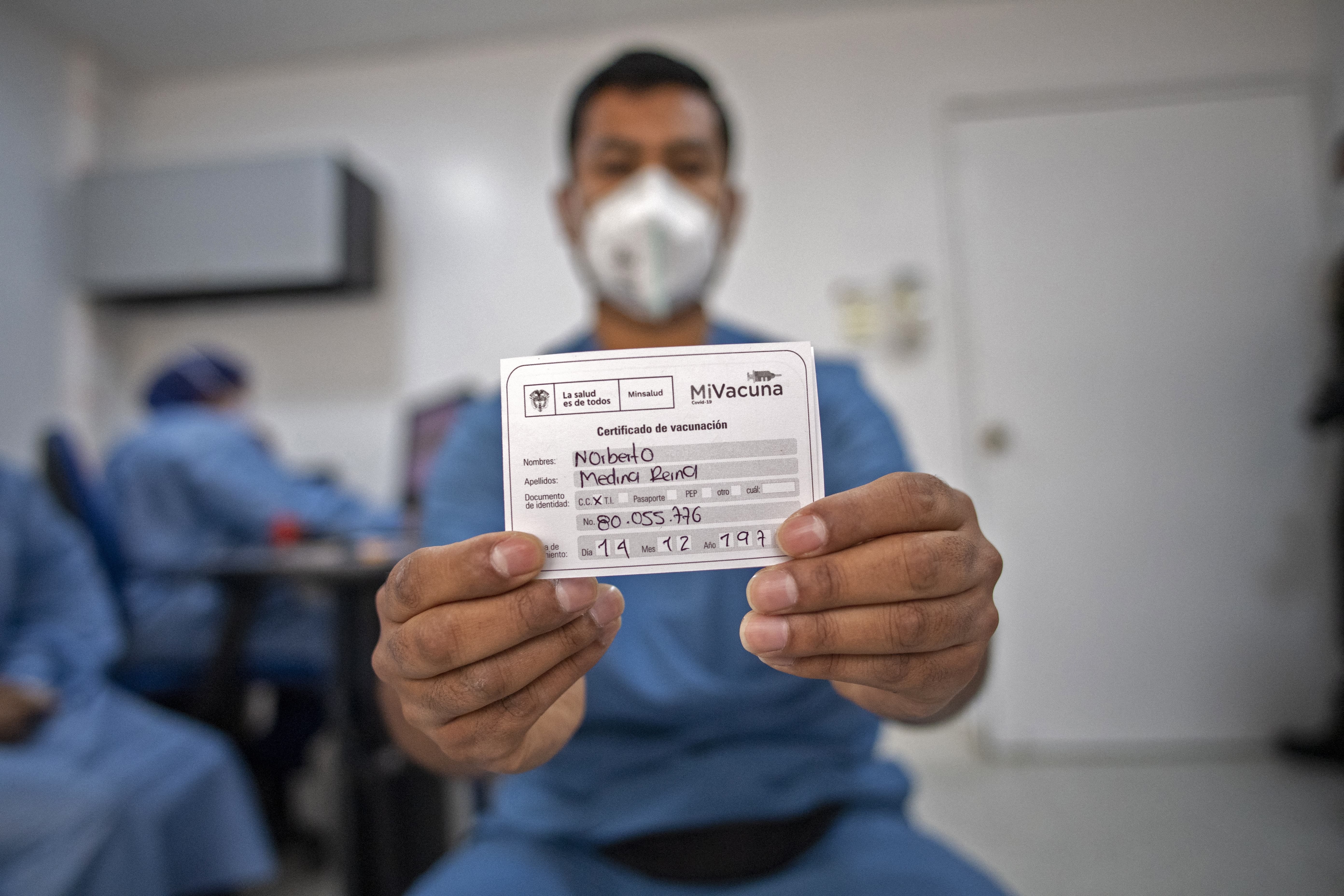 Medical doctor Norberto Medina shows a certificate after receiving the first dose of the COVID-19 vaccine in Bogota, on February 22, 2021. - Intensive care doctor Medina, 41, who was himself a COVID-19 critical patient, donated plasma and says that the fact of being about to die reaffirmed his vocation. (Photo by Juan BARRETO / AFP)