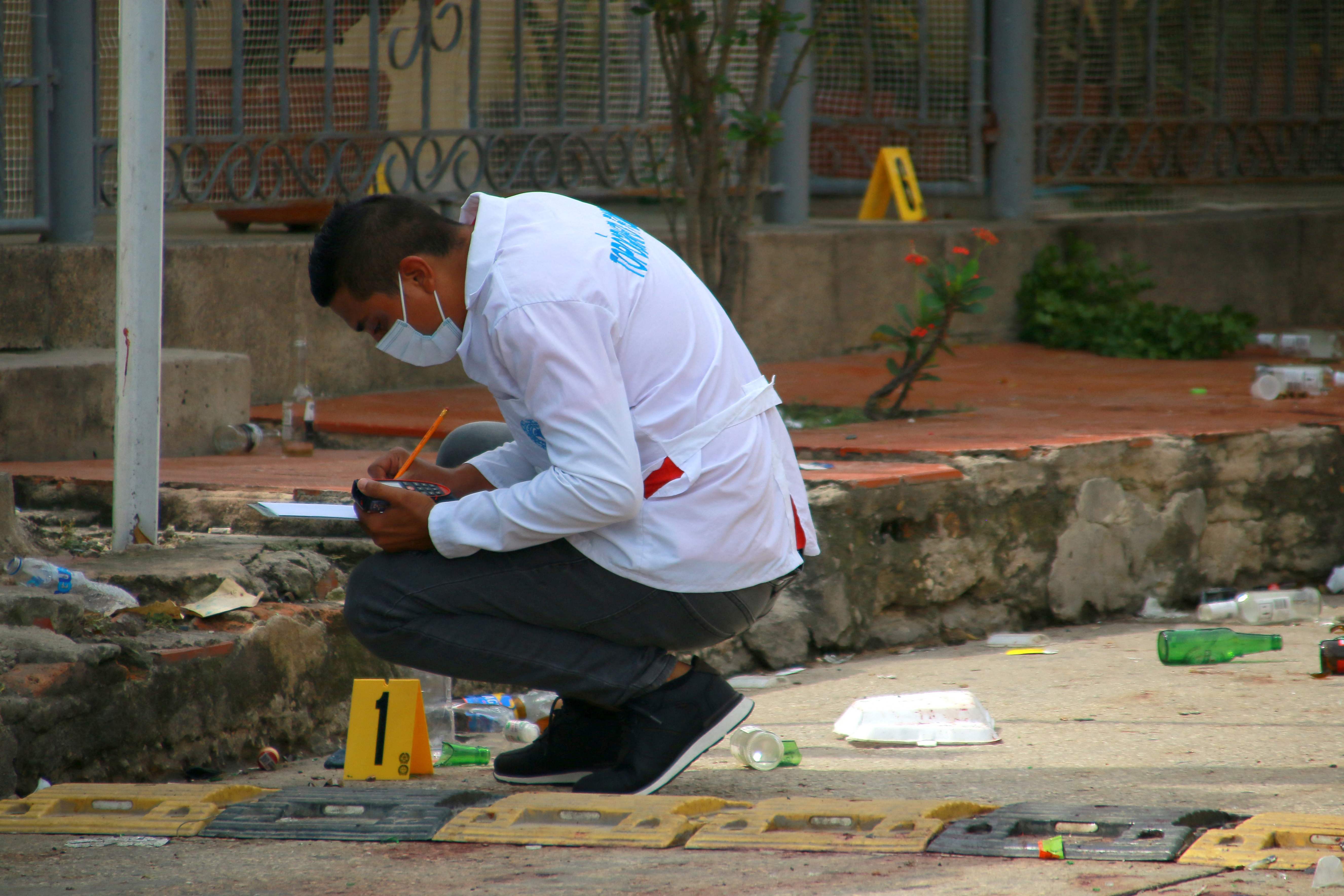 A member of the Colombian scientific police inspects outside the bar where six people were murdered by armed men at Las Flores neighborhood in Barranquilla, on September 12, 2022. (Photo by Jesus RICO / AFP)