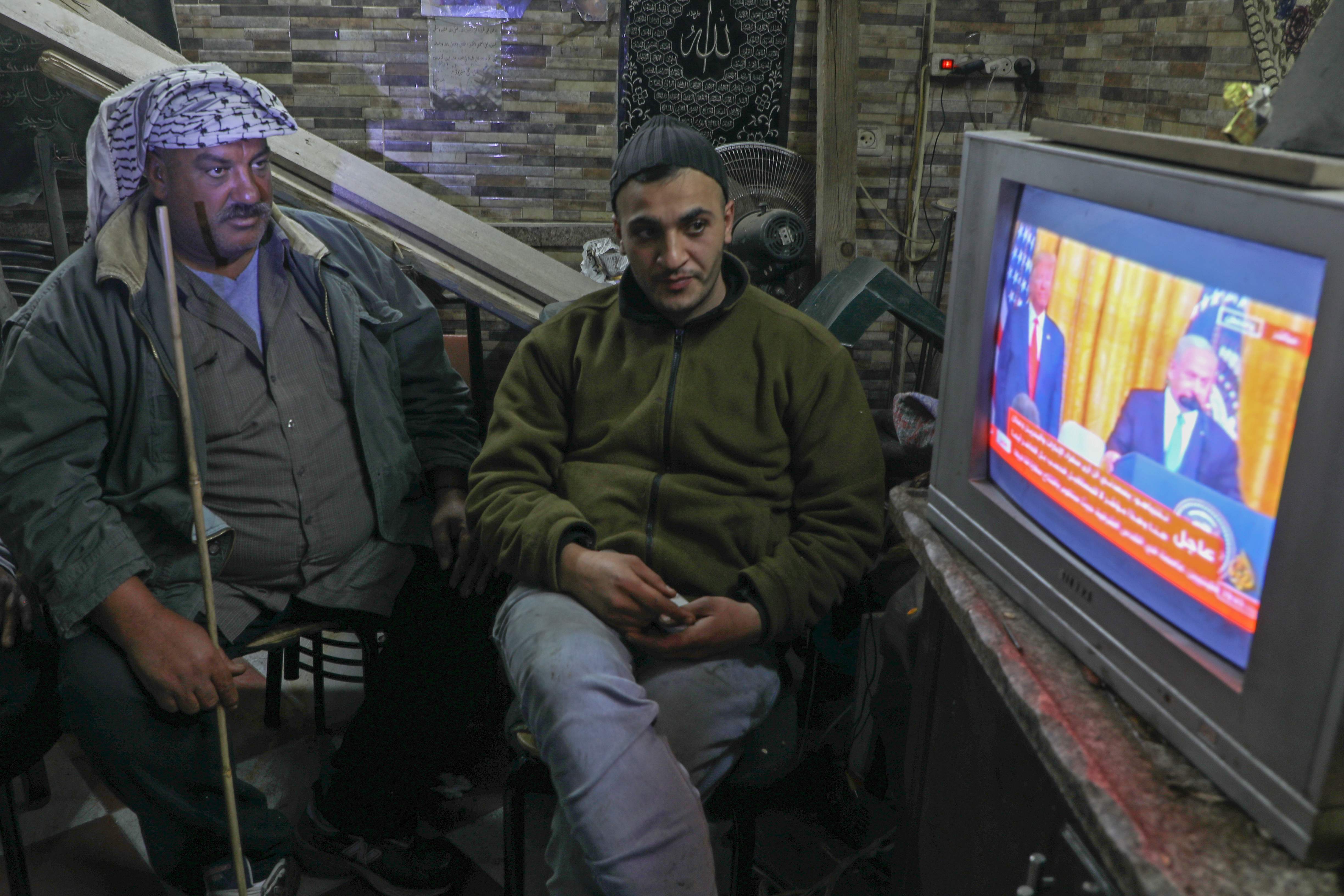Palestinians watch the televised press conference of US President Donald Trump and Israeli Prime Minister Benjamin Netanyahu in the Balatah refugee camp east of Nablus on January 28, 2020. - Palestinians staged protests against US President Donald Trump's Middle East peace plan, hours before it was to be unveiled in Washington. Thousands demonstrated in Gaza, burning pictures of Trump and the American flag, while further rallies were planned for the coming days. (Photo by Jaafar ASHTIYEH / AFP)