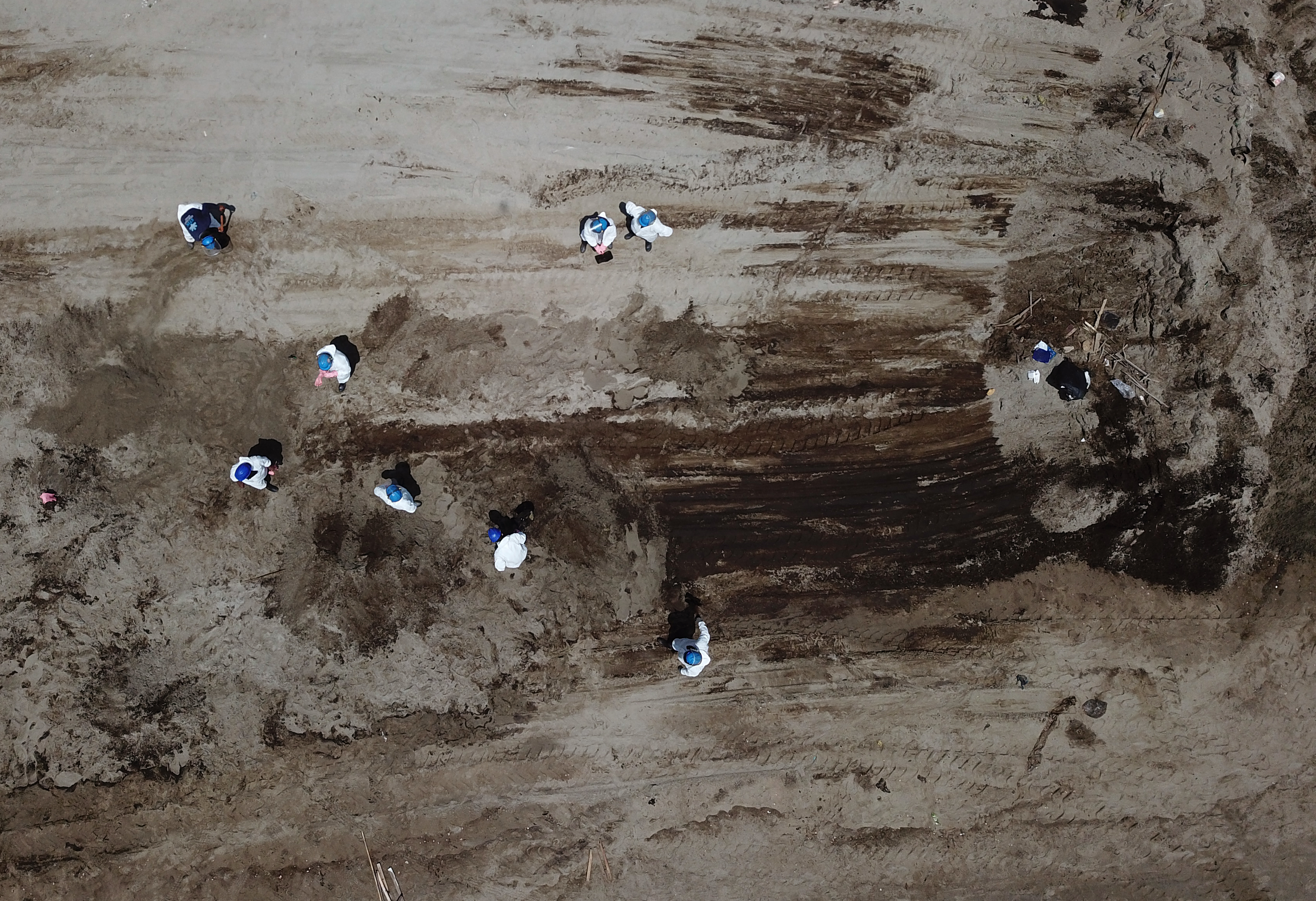 Aerial view showing cleaning crews work to remove oil from a beach in the Peruvian province of Callao on January 17, 2022, after a spill which occurred during the unloading process of the Italian-flagged tanker "Mare Doricum" at La Pampilla refinery caused by the abnormal waves recorded after the volcanic eruption in Tonga. - A massive volcanic eruption in Tonga triggered tsunami waves around the Pacific, with waves strong enough to drown two women in Peru, more than 10,000 kilometres (6,000 miles) away. (Photo by Cris BOURONCLE / AFP)