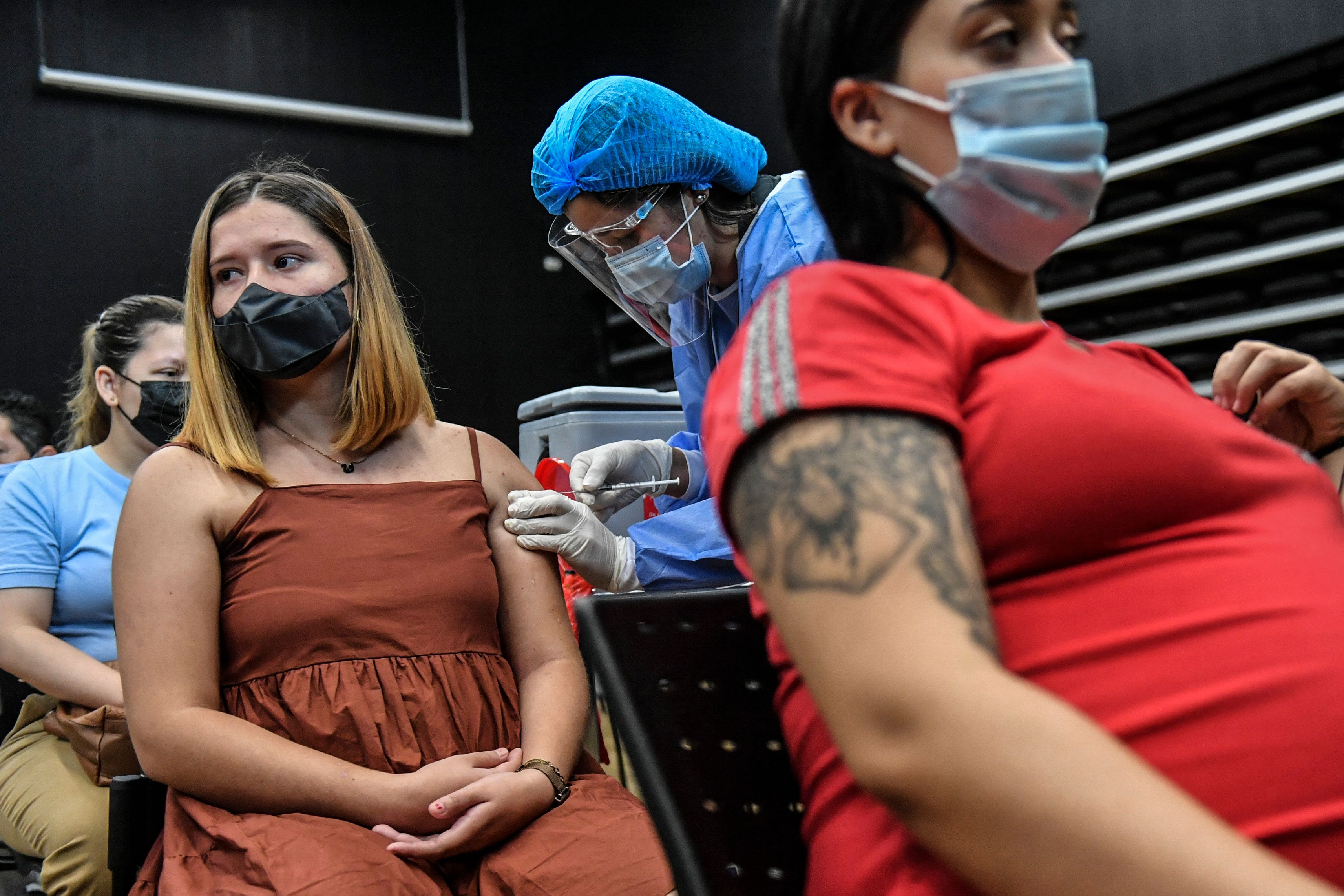A pregnant woman is inoculated with the Pfizer-BioNTech vaccine against COVID-19 at a vaccination center in Medellin, Colombia on July 24, 2021. - Colombia started to inoculate pregnant women who have three months of pregnancy or more. (Photo by JOAQUIN SARMIENTO / AFP)