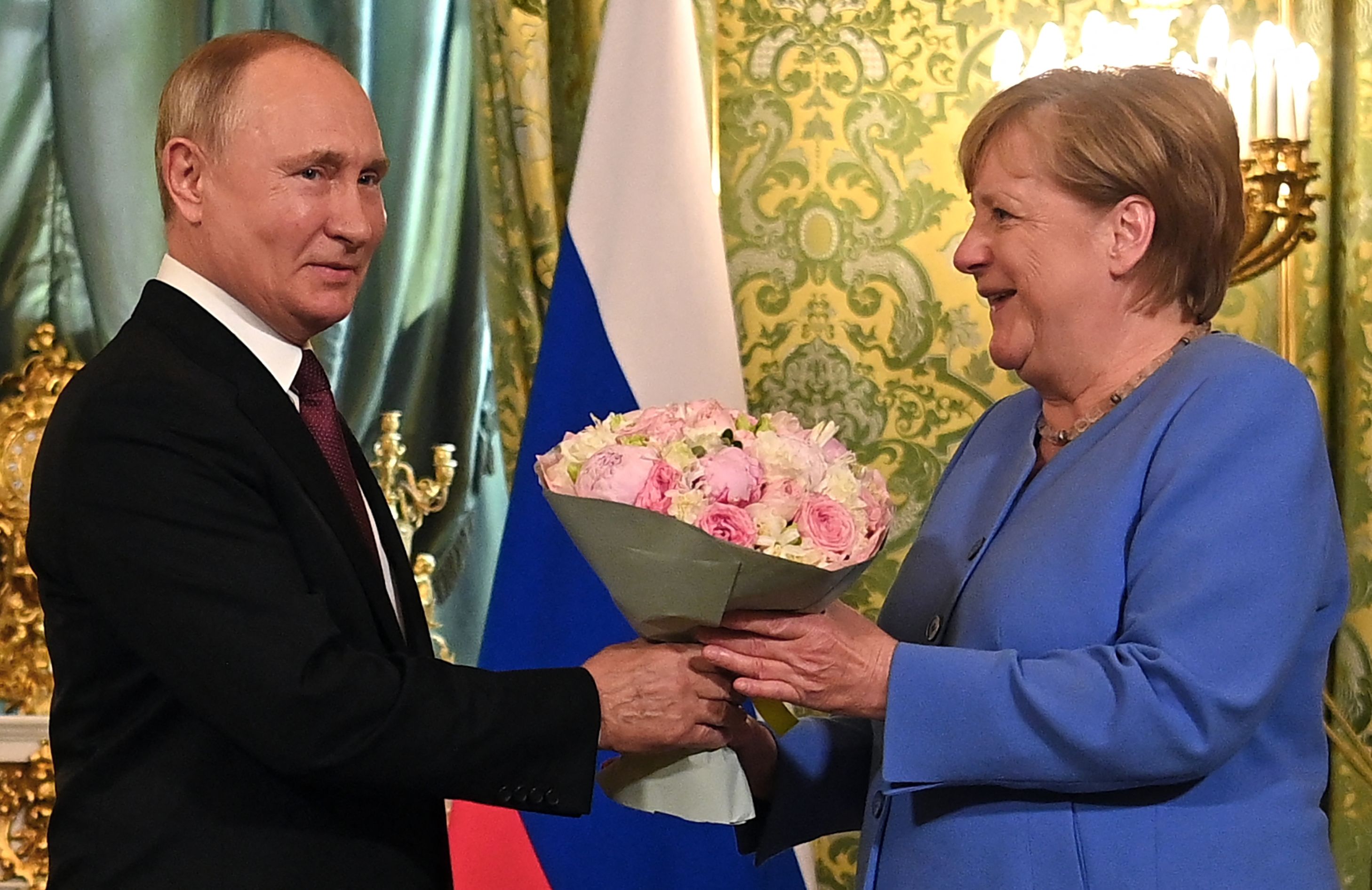 Russian President Vladimir Putin (L) welcomes German Chancellor Angela Merkel with a bouquet of flowers during their meeting at the Kremlin in Moscow on August 20, 2021. - The trip will be the 20th and last visit to Russia for Angela Merkel as German Chancellor, who bows out of politics following an election in Germany on September 26, 2021. (Photo by Evgeny ODINOKOV / SPUTNIK / AFP)