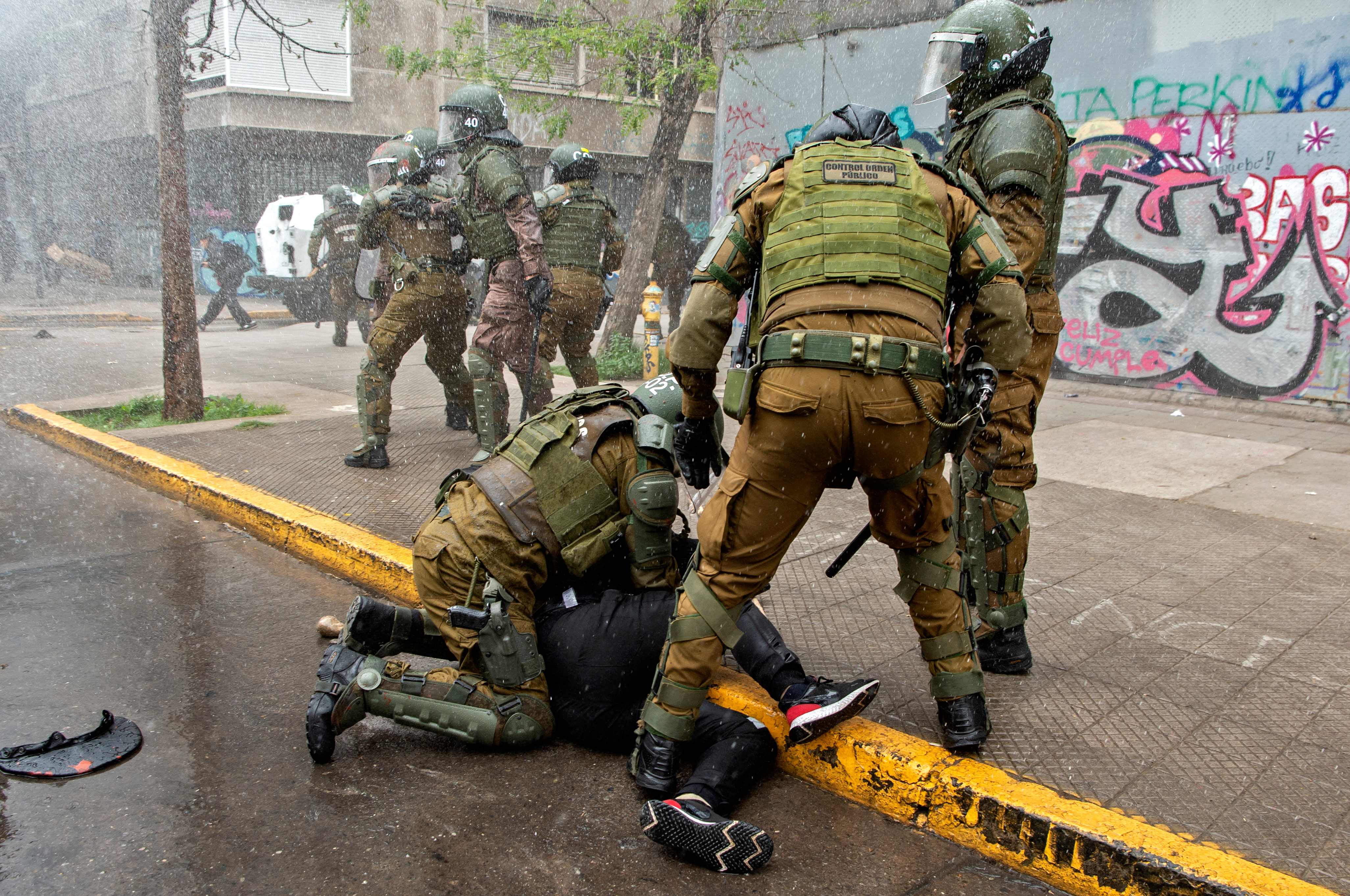 A demonstrator is arrested by riot policemen during clashes following a protest of mapuche indigenous people in downtown Santiago, on October 10, 2021, amid the commemoration of the Day of the Race. (Photo by Martin BERNETTI / AFP)