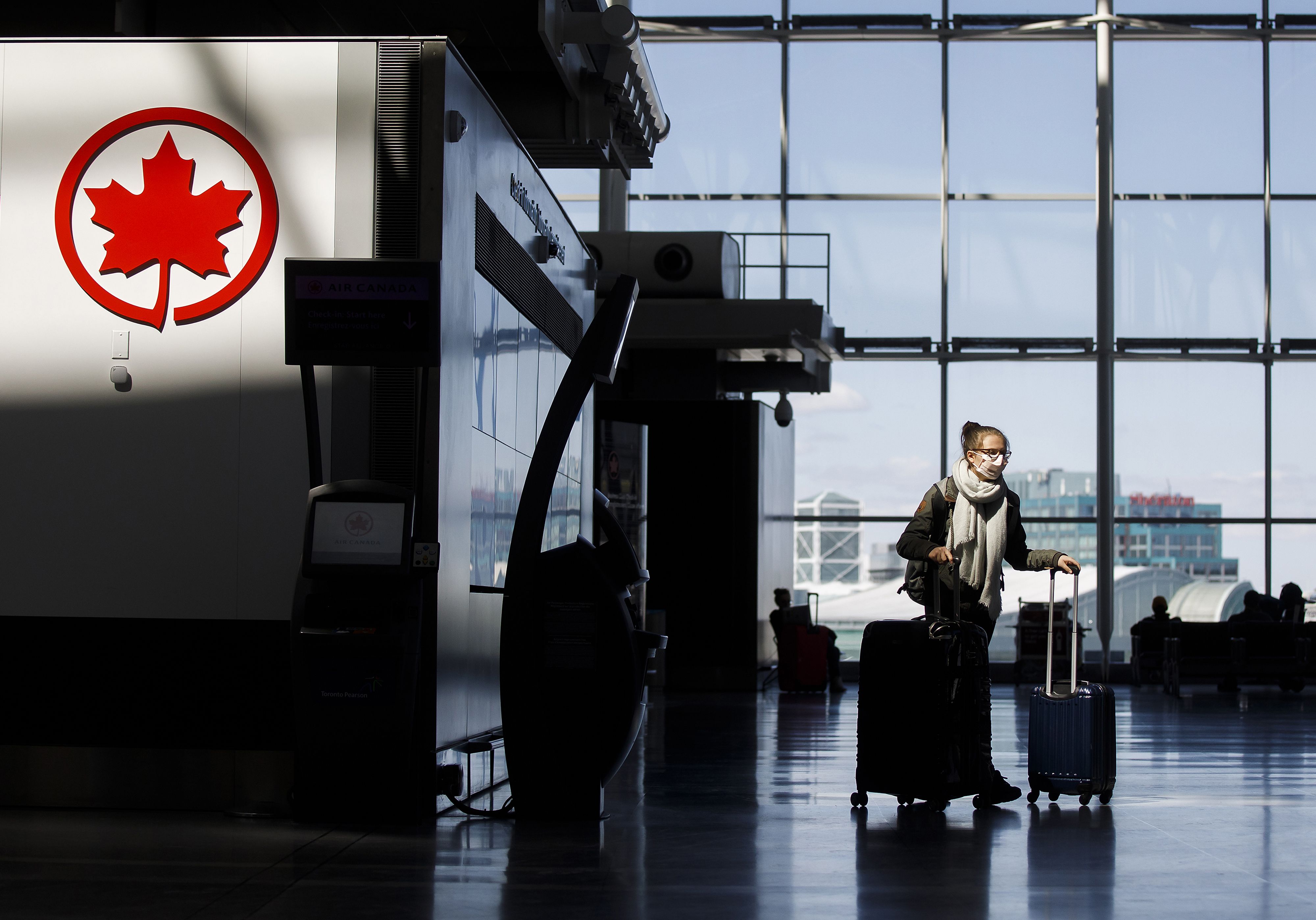 (FILES) In this file photo taken on April 1, 2020, a passenger wheels her luggage near an Air Canada logo at Toronto Pearson International Airport in Toronto, Canada. - Canada will require travellers to obtain a negative Covid-19 test before being allowed into the country, the government announced on December 30, 2020. (Photo by Cole Burston / GETTY IMAGES NORTH AMERICA / AFP)
