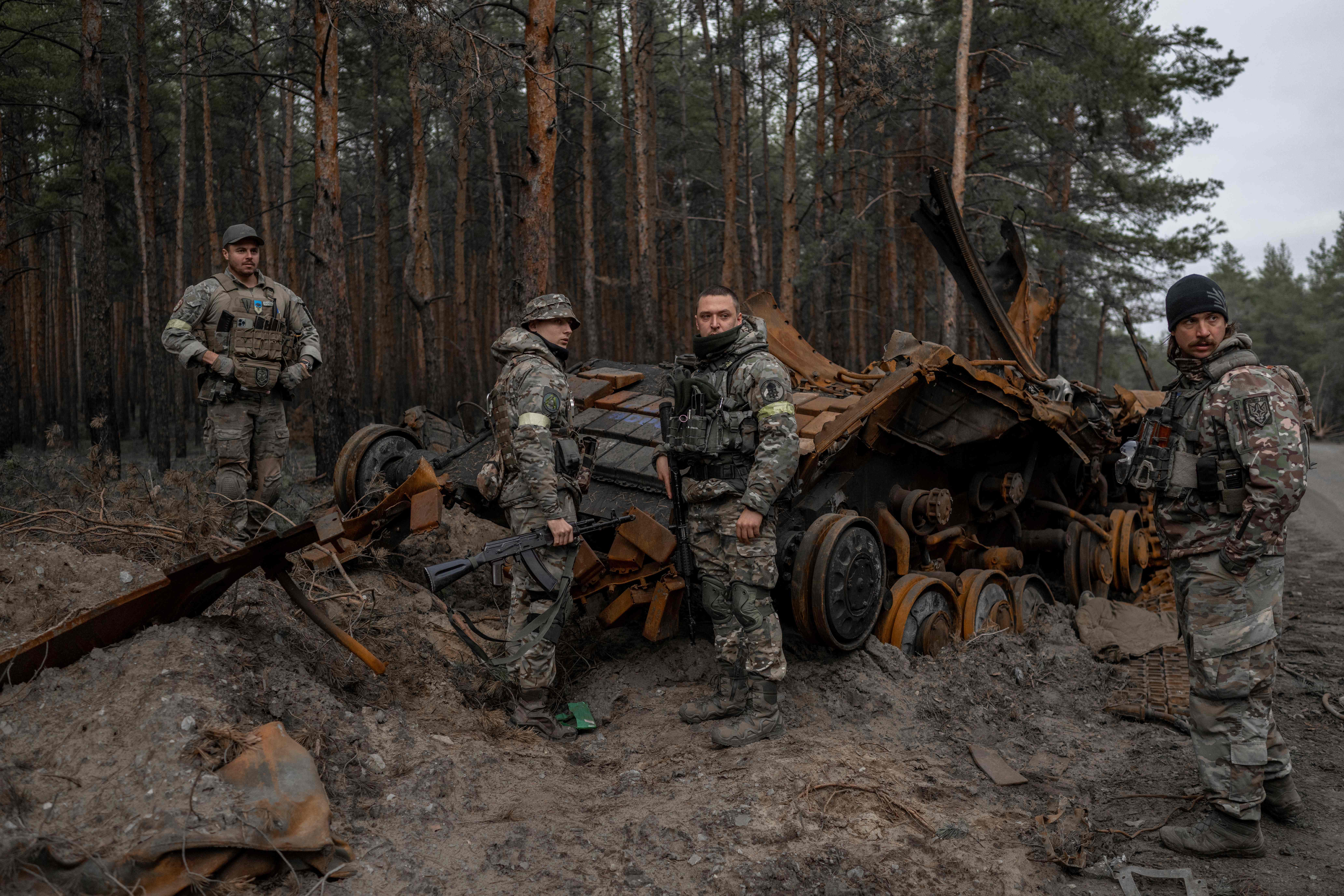 Ukrainian soldiers and volunteer fighters inspect a destroyed Russian tank in an undisclosed location, eastern Ukraine on November 10, 2022, amid the Russian invasion of Ukraine. (Photo by BULENT KILIC / AFP)