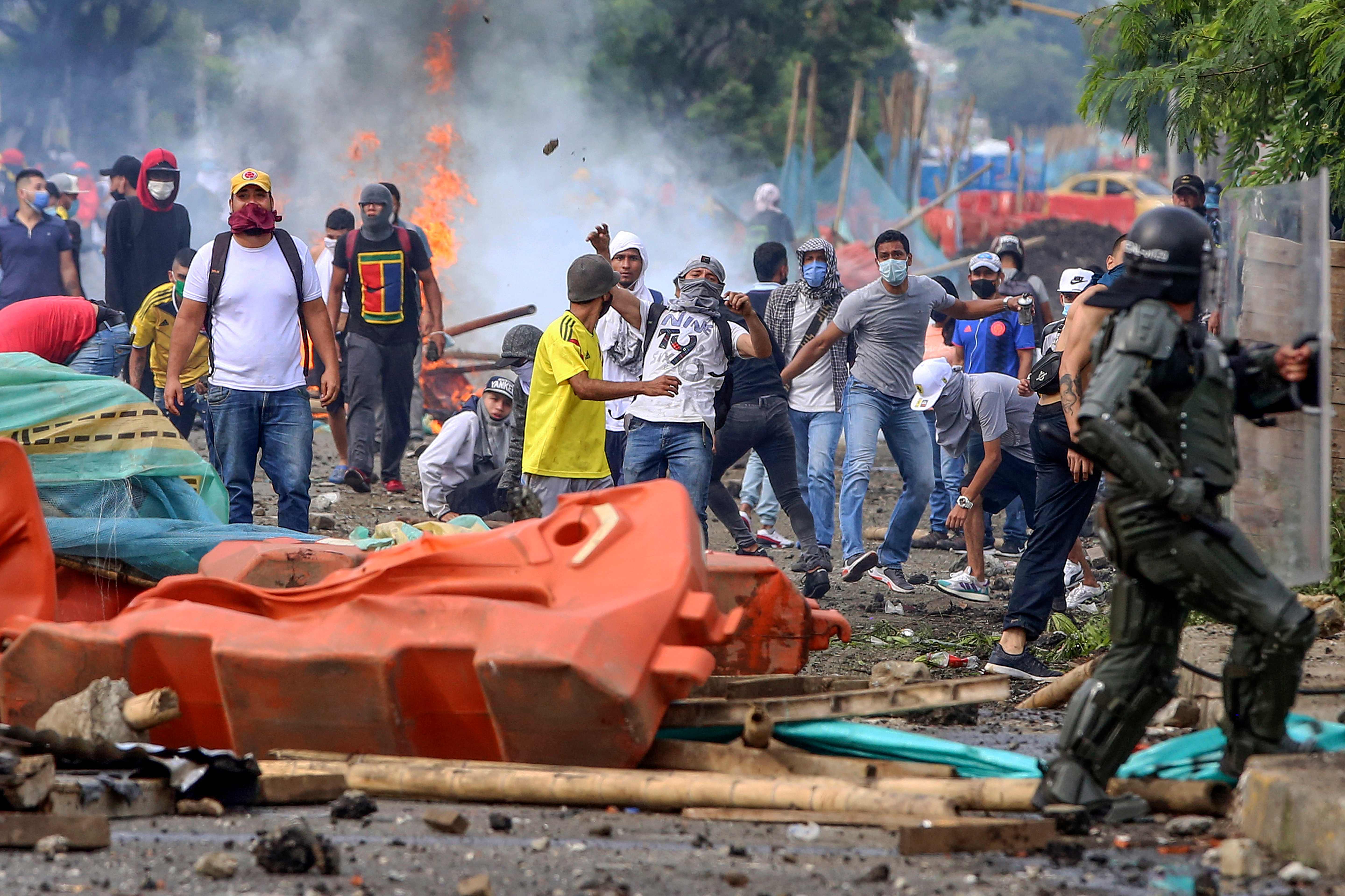 Demonstrators clash with riot police during a protest against a tax reform bill launched by Colombian President Ivan Duque, in Cali, Colombia on April 29, 2021. - Workers' unions, teachers, civil organizations, indigenous people and other sectors reject the project that is underway in the Congress, considering that it punishes the middle class and is inappropriate in the midst of the crisis unleashed by the COVID-19 pandemic. (Photo by Paola MAFLA / AFP)