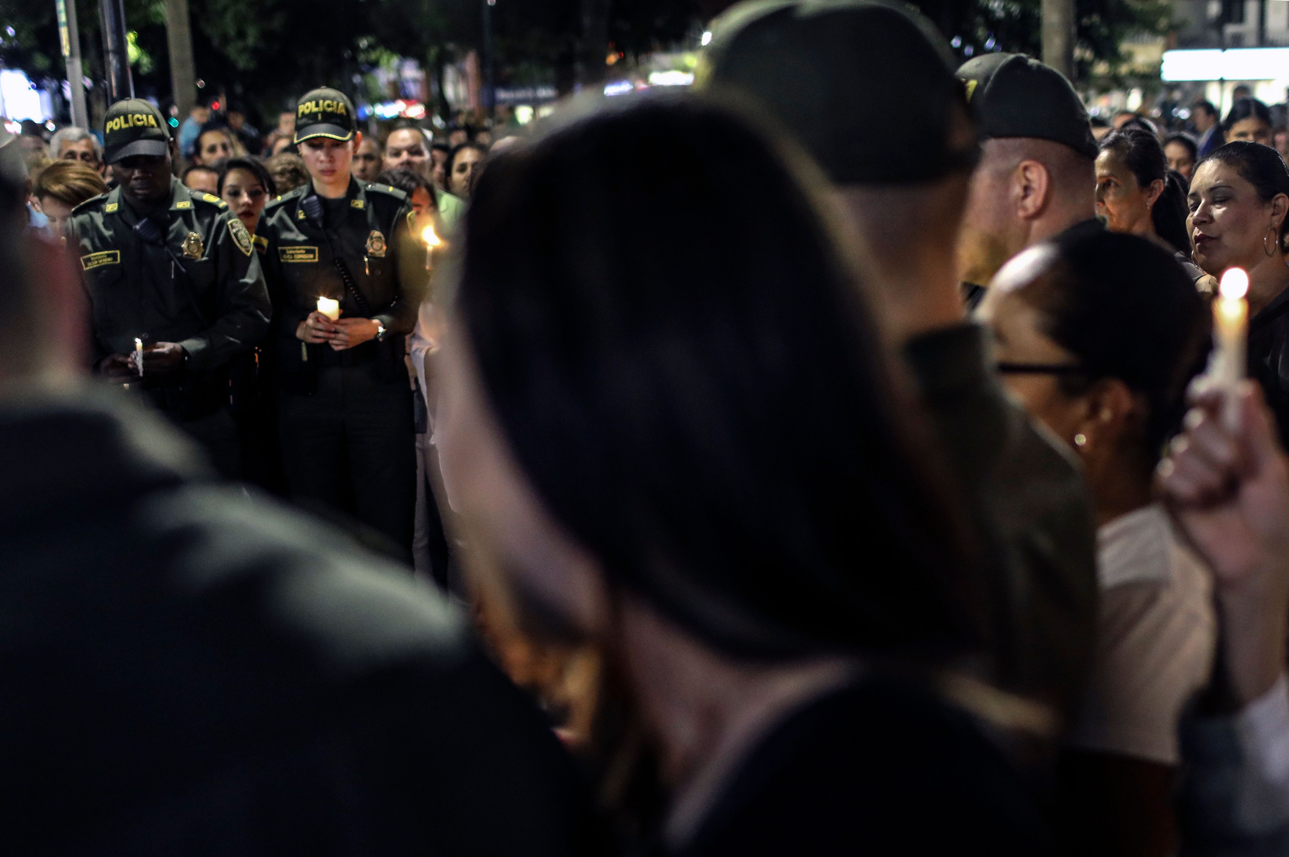 Police members and civilians hold candles during a tribute to the victims of the Bogota car bomb attack, in Itagui, near Medellin, Antioquia department, Colombia, on January 19, 2019. - The Colombian government on Friday blamed leftist ELN rebels for Thursday's bombing of a police academy in Bogota that killed 20 people as well as the attacker, and dealt a body blow to the peace process. President Ivan Duque reinstated arrest warrants for 10 ELN peace negotiators who are part of the guerrilla group's delegation to the Cuba talks. (Photo by JOAQUIN SARMIENTO / AFP)