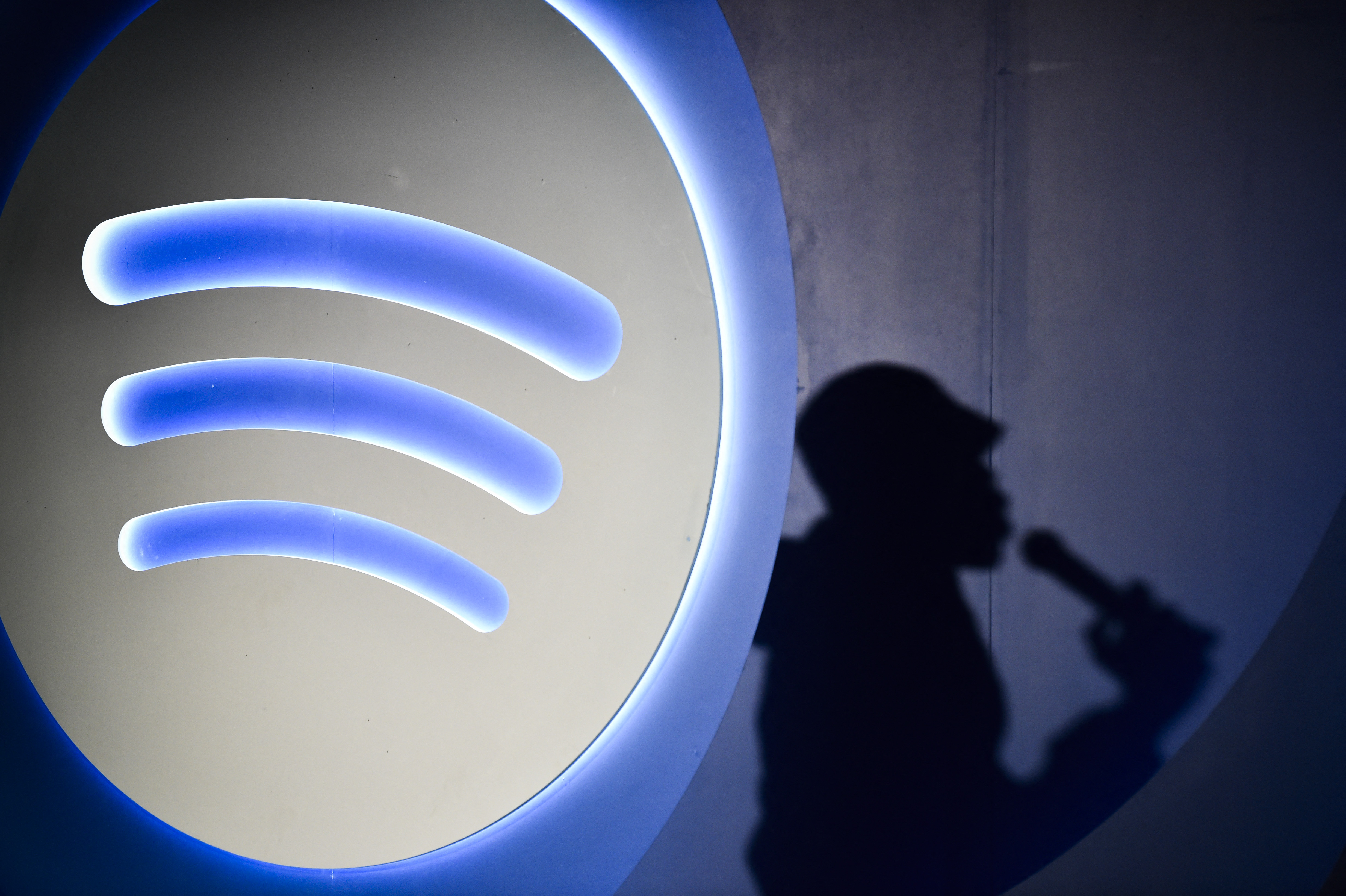 La sombra de Xavier X. Jernigan, el locutor DJ de Inteligencia Artificial de Spotify, aparece mientras asiste a la presentación de la última herramienta de Spotify en Ciudad de México el 17 de julio de 2024. Una creciente ola de bandas de inteligencia artificial (IA) está marcando el comienzo de una nueva era donde el trabajo será más escaso para los músicos. Ya sea el rock estilo años 70 de Velvet Sundown o los proyectos de música country "Aventhis" y "The Devil Inside", bandas cuyos miembros son creaciones puramente de IA están obteniendo más de un millón de reproducciones en el gigante de streaming Spotify. (Foto de Rodrigo Oropeza / AFP)