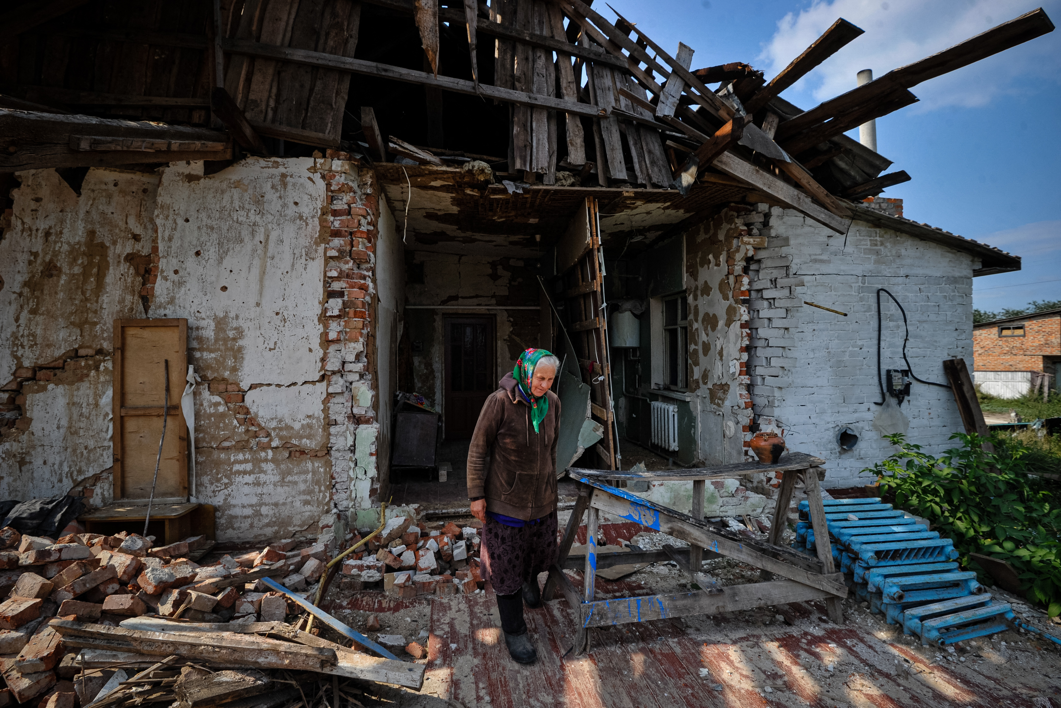 Tatyana, 69, walks in front of her destroyed house in the village of Lukashivka, Chernihiv region, on September 7, 2022, amid the Russian invasion of Ukraine. (Photo by SERGEI CHUZAVKOV / AFP)