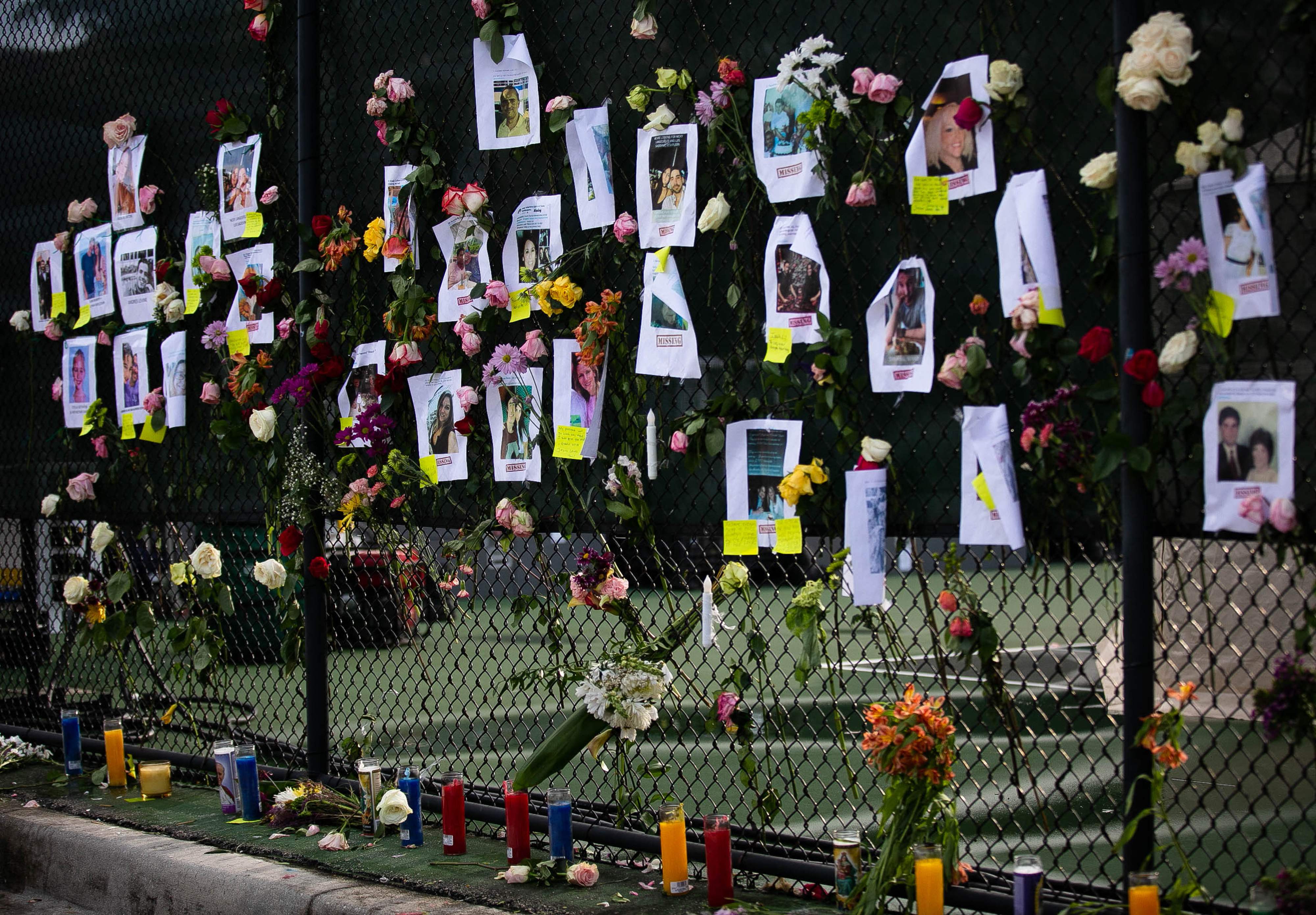 Photos of missing residents are posted at a makeshift memorial at the site of a collapsed building in Surfside, Florida, north of Miami Beach,on June 26, 2021. - An engineer warned of "major structural damage" at a Florida apartment building three years before it partially collapsed, a report said June 26, as rescuers raced to find 159 people still unaccounted for in the mountain of debris. Four people have been confirmed dead after the 12-story oceanfront building in Surfside pancaked as residents slept inside in the early hours of June 24. (Photo by Andrea SARCOS / AFP)