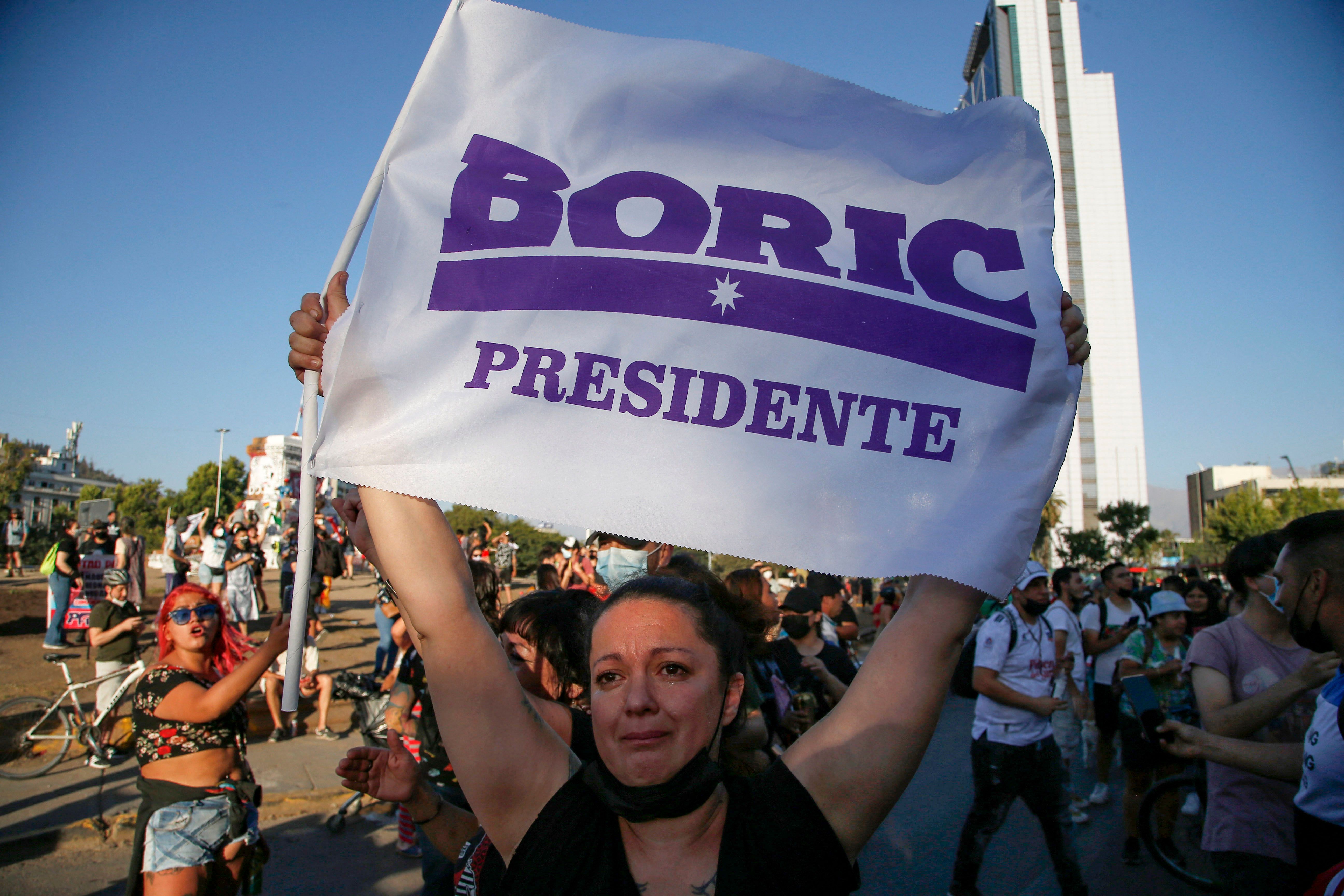Supporters of Chilean president-elect Gabriel Boric celebrate following the official results of the runoff presidential election, in Santiago, on December 19, 2021. - With more than 99 percent of ballots counted, leftist lawmaker Gabriel Boric, 35, became Chile's youngest-ever president leading with 55.86 percent to 44 percent for his far-right rival Jose Antonio Kast, said the Servel website, with a star to indicate the winner. (Photo by CLAUDIO REYES / AFP)