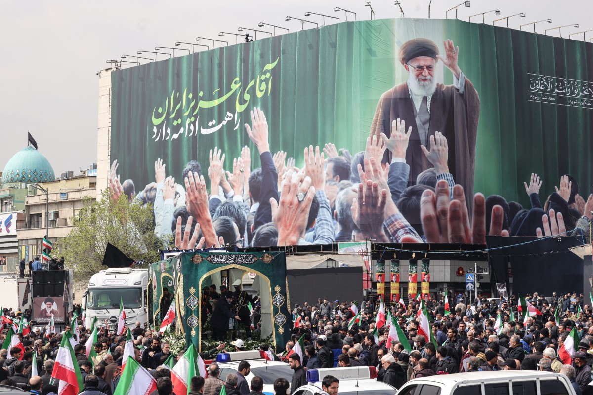Iraníes se reúnen junto a un cartel que representa al líder supremo iraní abatido, el ayatolá Ali Khamenei, mientras asisten a los funerales de comandantes de la Guardia Revolucionaria de Irán (IRGC).
