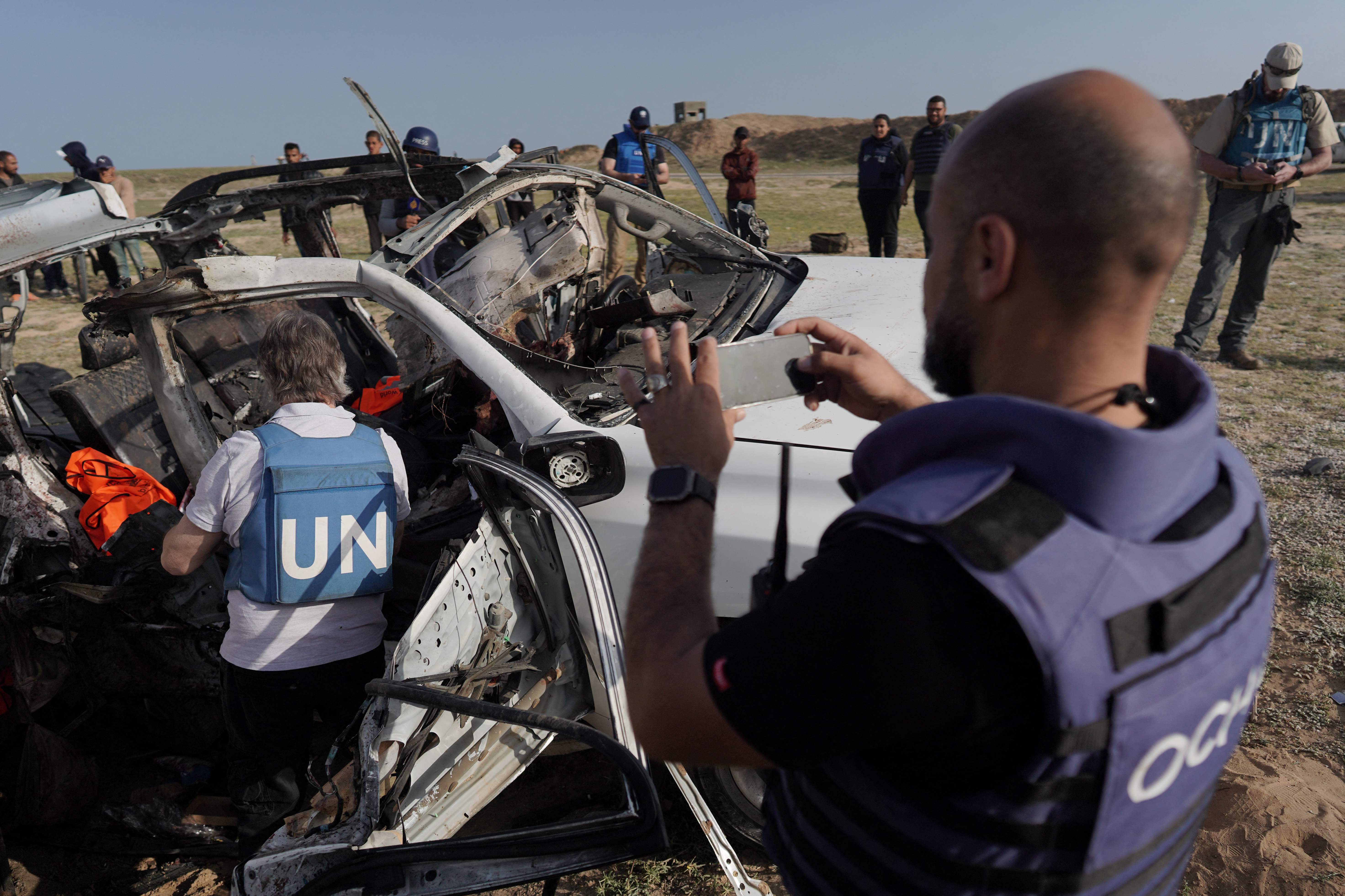 EDITORS NOTE: Graphic content / TOPSHOT - United Nations staff members inspect the carcass of a car used by US-based aid group World Central Kitchen, that was hit by an Israeli strike the previous day in Deir al-Balah in the central Gaza Strip on April 2, 2024, amid the ongoing battles between Israel and the Palestinian militant group Hamas. The international food aid charity said on April 2 it was pausing its Gaza aid operations after seven of its staff were killed in a "targeted Israeli strike" as they unloaded desperately needed food aid delivered by sea from Cyprus. (Photo by AFP)