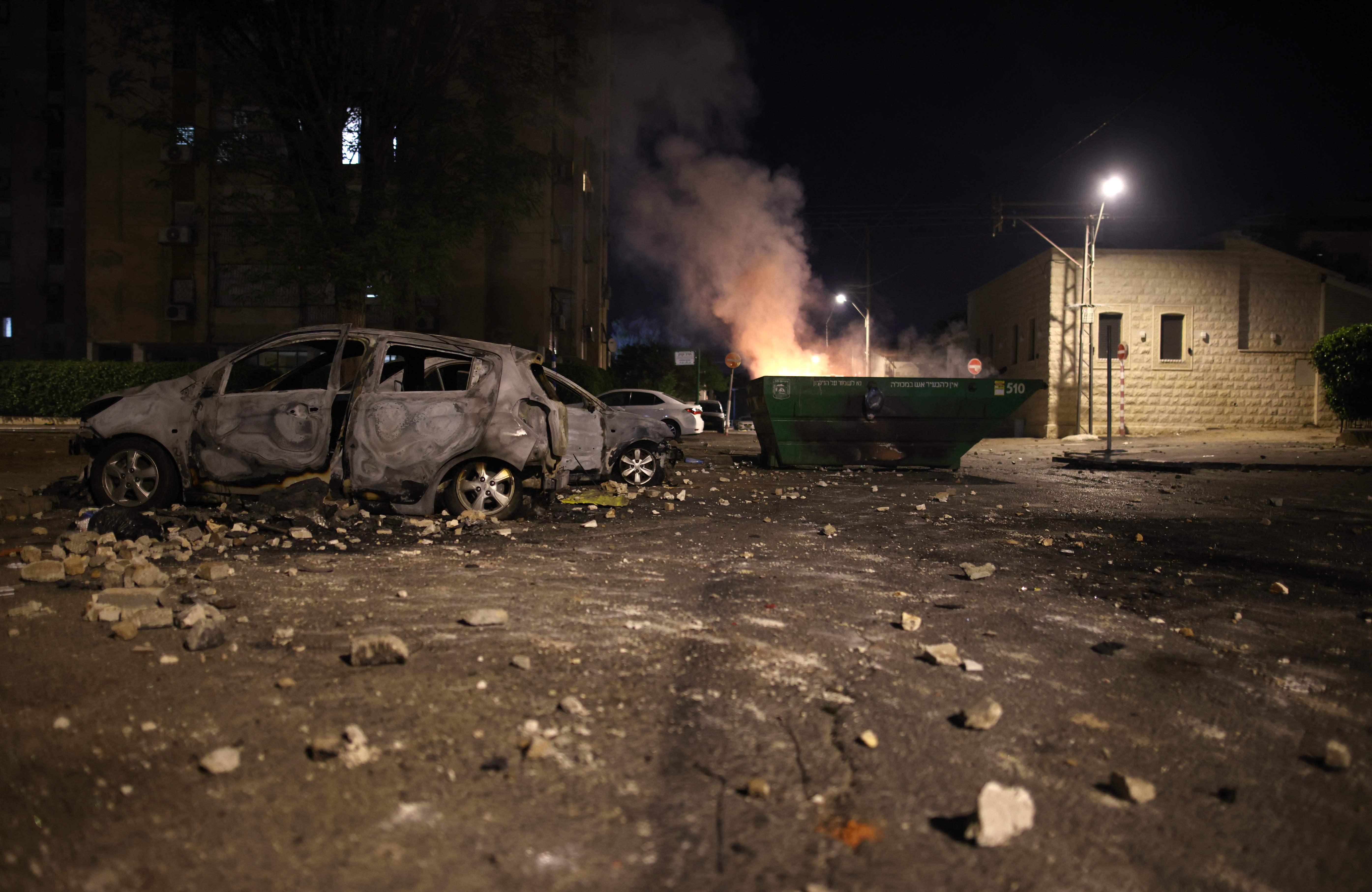 A picture shows burnt cars and trash container in the mixed Jewish-Arab city of Lod on May 13, 2021, during clashes between Israeli far-right extremists and Arab-Israelis. (Photo by ahmad gharabli / AFP)