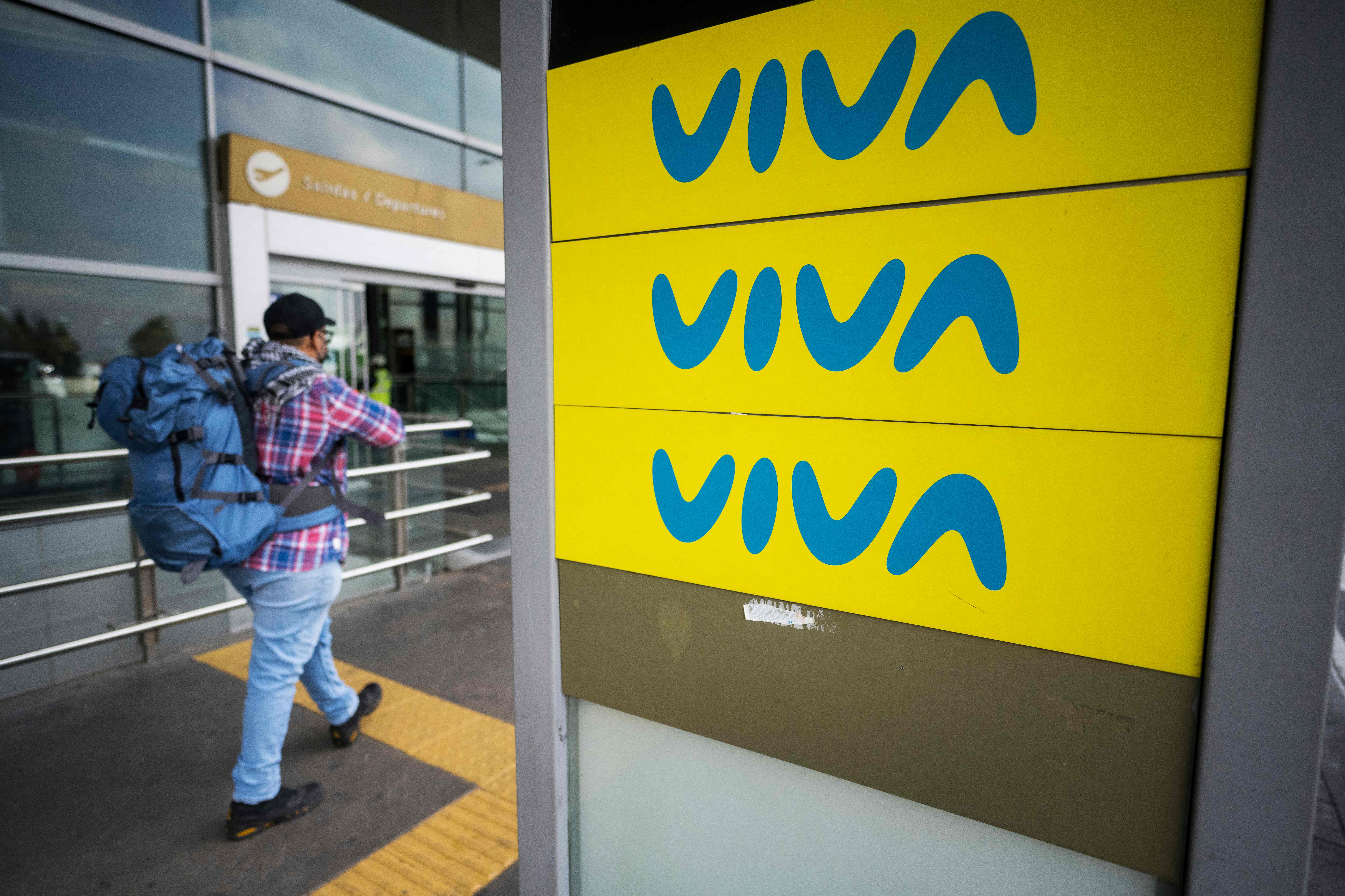A man passes by an advertising board of Viva Air outside the El Dorado international airport in Bogota on February 28, 2023. - The Colombian low-cost airline Viva Air suspended its operations last Monday due to financial problems, according to a company statement. (Photo by Juan Barreto / AFP)