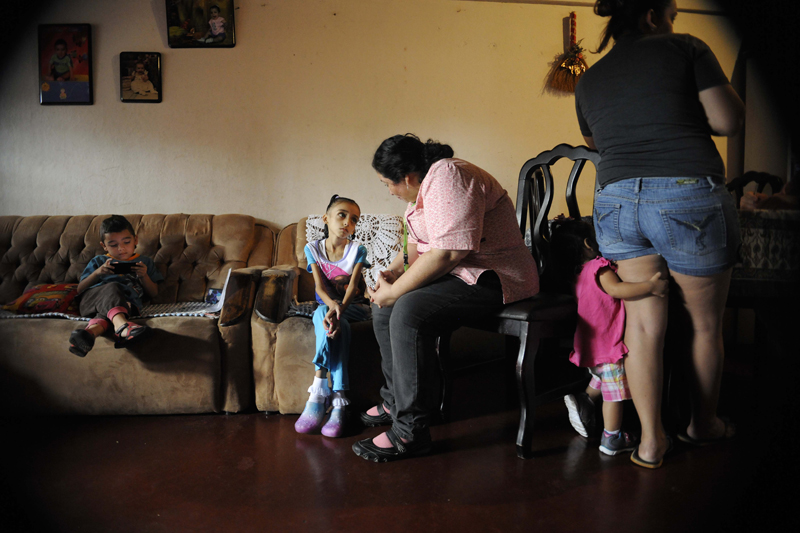 Naydelin Ruiz Alvarado tiene 9 años y un tumor de hígado. La sicóloga de la Unidad de Cuidado Paliativo del Hospital de Niños, Ligia Obando, la visitó en su casa, en Alajuelita, junto a un médico y una enfermera. A su lado, sus hermanos, Ian y Dana, y su mamá, Rocío, quien escuchó los consejos del médico Luis Madrigal. Estas visitas las reciben 1.070 niños pero las necesitan muchos más. (Foto con permiso de la familia) | DIANA MÉNDEZ