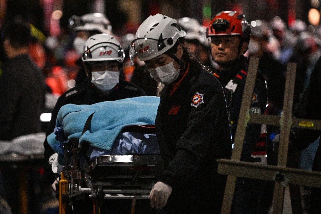 A victim of a Halloween crush, which left at least 120 people dead, is transported on a stretcher in the district of Itaewon in Seoul on October 30, 2022. - At least 120 people were killed on October 29 and some 100 were injured in a stampede in central Seoul when thousands crowded into narrow streets to celebrate Halloween, officials said. (Photo by Anthony WALLACE / AFP)