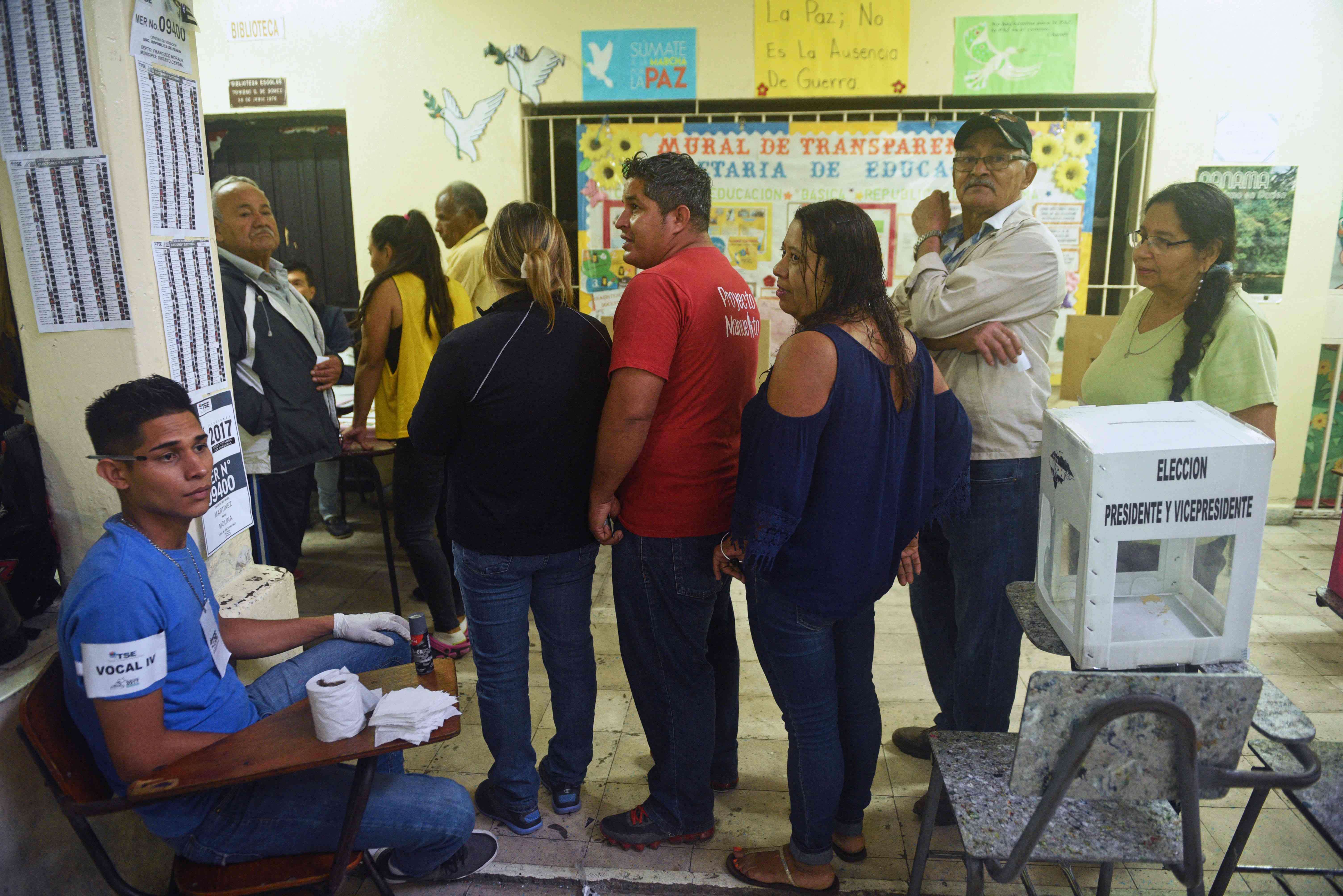 Voters queue to cast their ballots at a polling station in Tegucigalpa during the general election, on November 26, 2017.
Honduras' six million voters are to cast ballots in a controversial election Sunday in which President Juan Orlando Hernandez is seeking a second mandate despite a constitutional one-term limit. This small country is at the heart of Central America's "triangle of death," an area plagued by gangs and poverty. / AFP PHOTO / RODRIGO ARANGUA