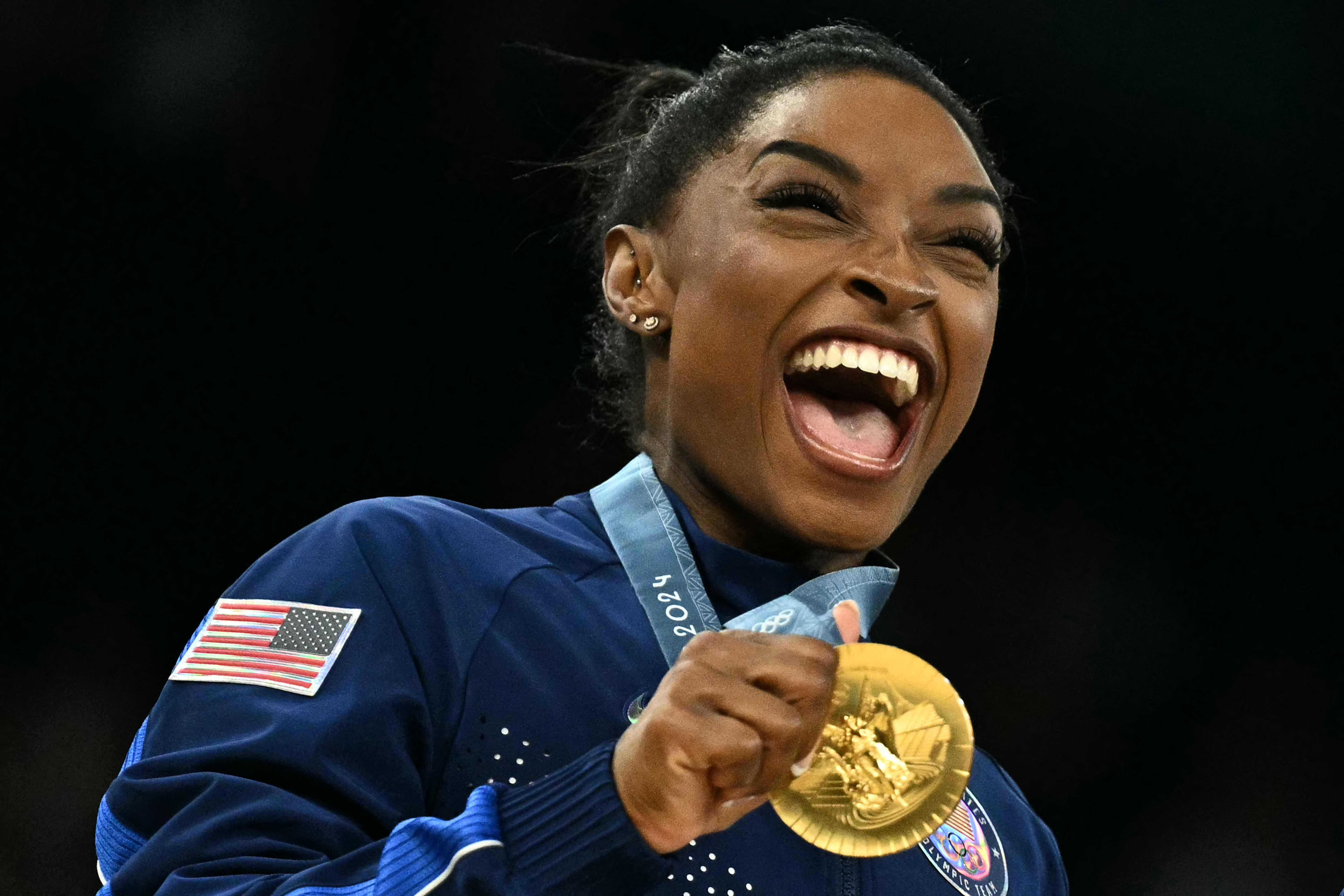 TOPSHOT - US' Simone Biles poses with the gold medal during the podium ceremony for the artistic gymnastics women's team final during the Paris 2024 Olympic Games at the Bercy Arena in Paris, on July 30, 2024. (Photo by Lionel BONAVENTURE / AFP)