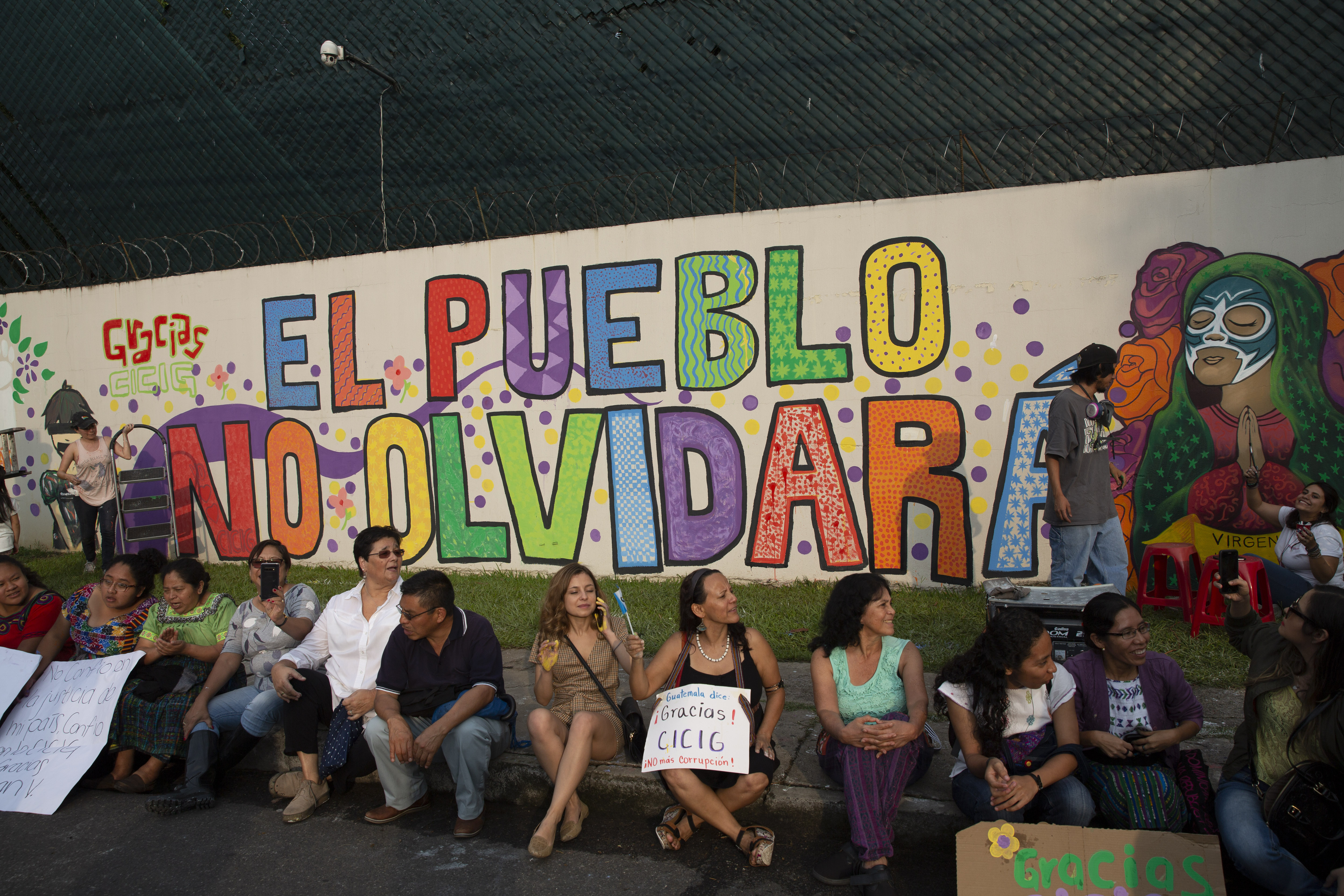 Artists and activists pose for photos next to a mural at the United Nations International Commission Against Impunity, CICIG, headquarters in Guatemala City, Saturday, Aug. 31, 2019. The UN mission is closing its operation after 12 years. It brought to trial three former presidents and hundreds of businessmen, officials, judges and individuals accused of corruption in the Central American country. (AP Photo/Moises Castillo)