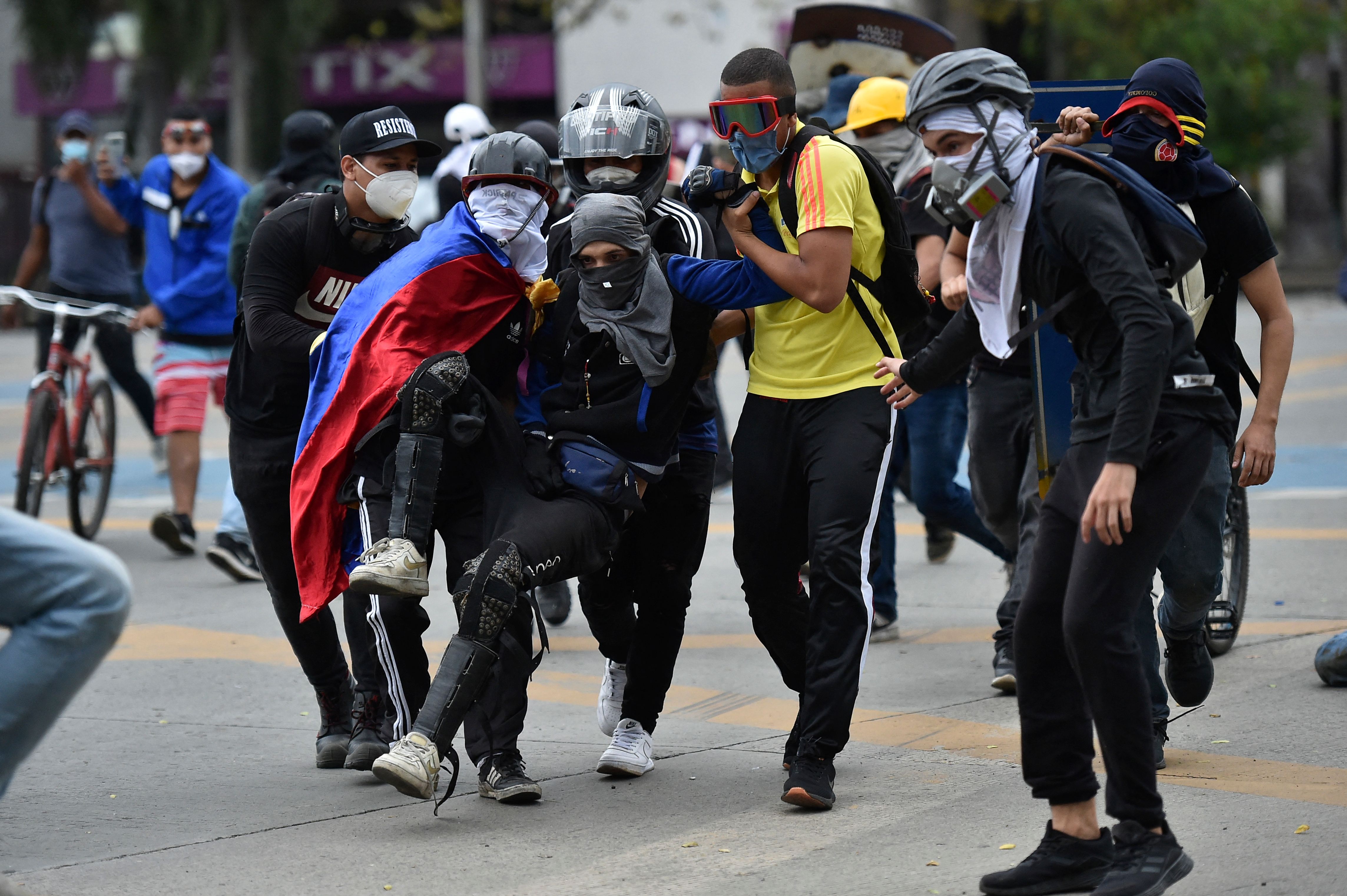 (FILES) In this file photo taken on May 28, 2021 a man in helped by fellow demonstrators after being reached by a bullet during clashes with the police in the framework of a new protest against the government of Colombian President Ivan Duque, in Cali, Colombia. - United Nations High Commissioner for Human Right Michelle Bachelet expressed concern on May 30, 2021 for the violence shaking Cali, under military control in the framework of protests against the government and asked for an "independent" investigation of the deaths, around a dozen. (Photo by Luis ROBAYO / AFP)
