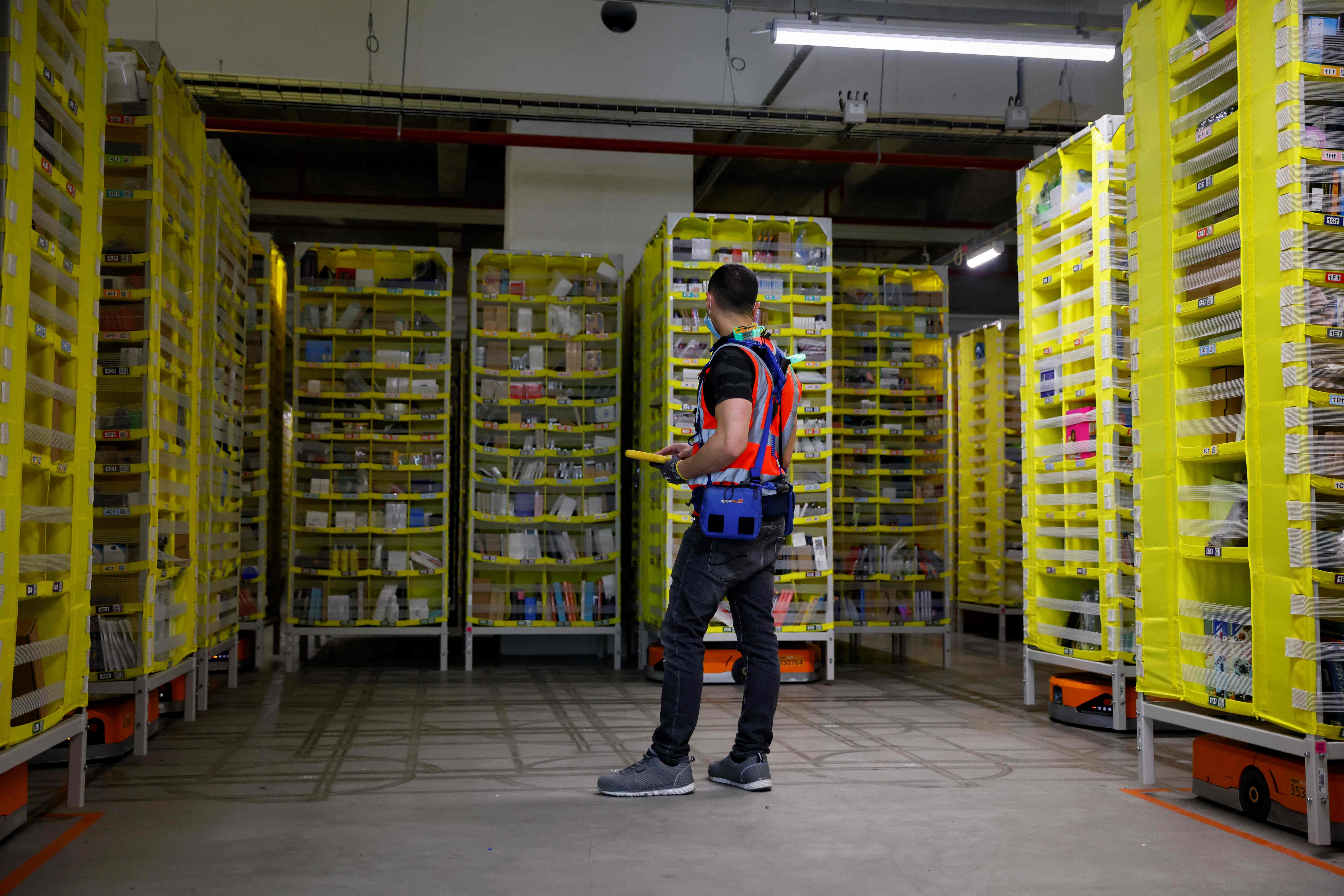 (FILES) In this file photo taken on December 14, 2021 a maintenance employee works in a robotic warehouse at the Amazon's centre of Bretigny-sur-Orge. - Amazon announced on January 4, 2022 it will cut more than 18,000 jobs from its workforce, citing "the uncertain economy" and the fact that the online retail giant had "hired rapidly" during the pandemic. (Photo by Thomas SAMSON / AFP)