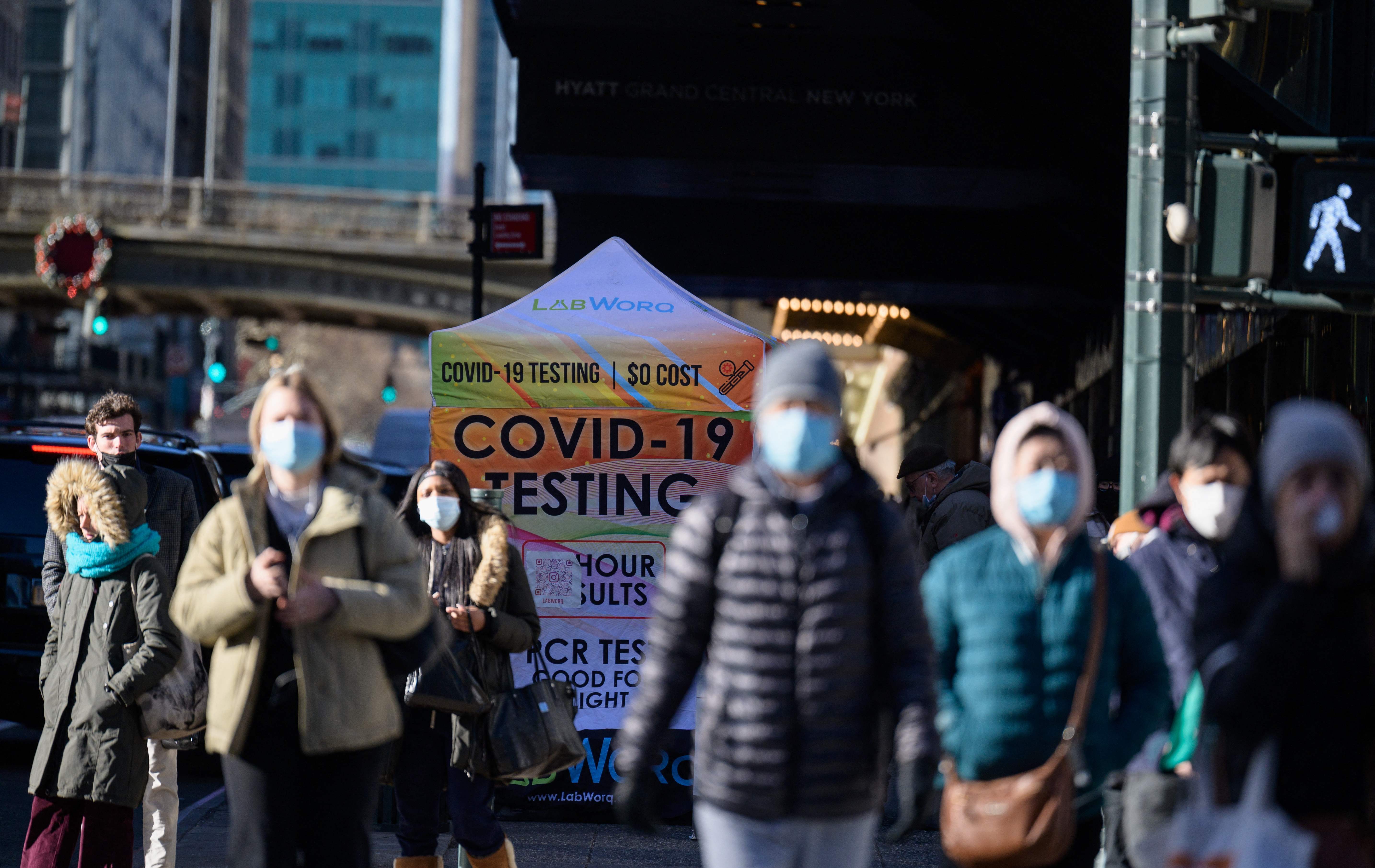 People walk past a Covid-19 testing station on January 4, 2022, in New York. - The US recorded more than 1 million Covid-19 cases on January 3, 2022, according to data from Johns Hopkins University, as the Omicron variant continues to spread at a blistering pace. Johns Hopkins also reported 1,688 deaths for the same period, a day after top US pandemic advisor Anthony Fauci had said the country is experiencing "almost a vertical increase" in Covid-19 cases but the peak may be only weeks away. (Photo by ANGELA WEISS / AFP)