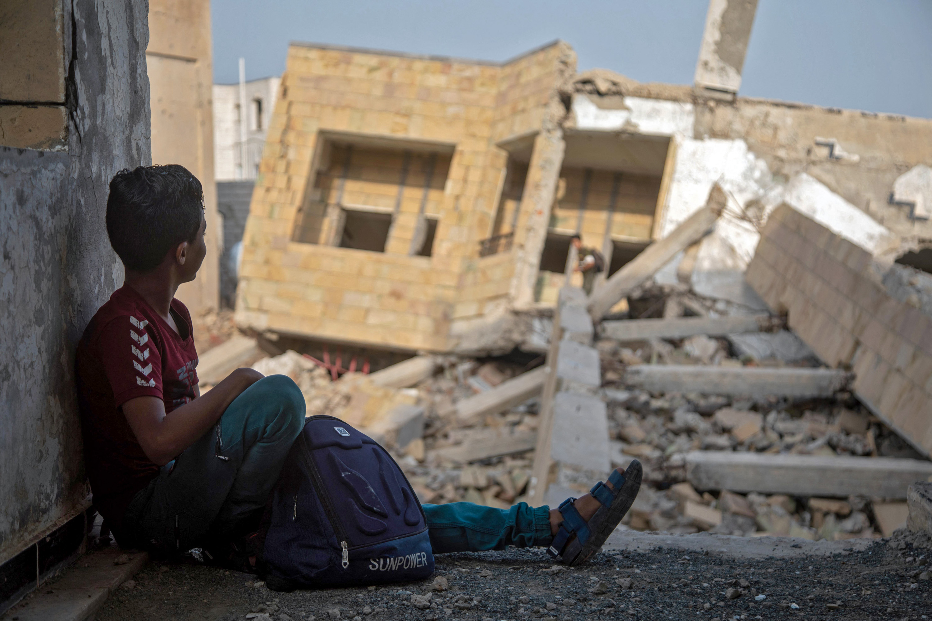 Yemeni students attend class in their destroyed school compound on the first day of the new academic year in the country's third-city of Taez on August 30, 2021. (Photo by AHMAD AL-BASHA / AFP)