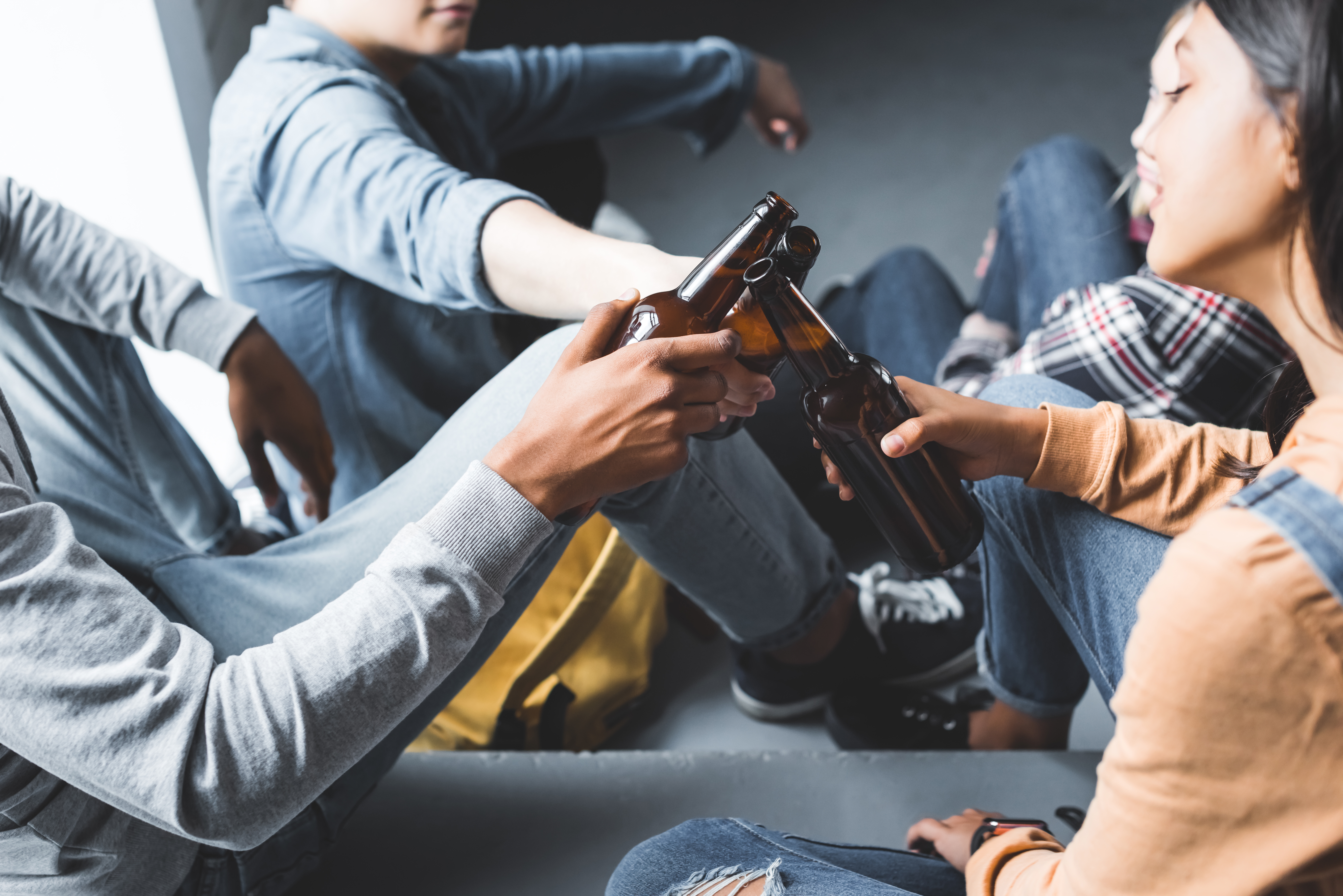 Adolescentes y jóvenes consumiendo cervezas, bebidas alcohólicas, alcohol. Menores de edad brindando con sus botellas