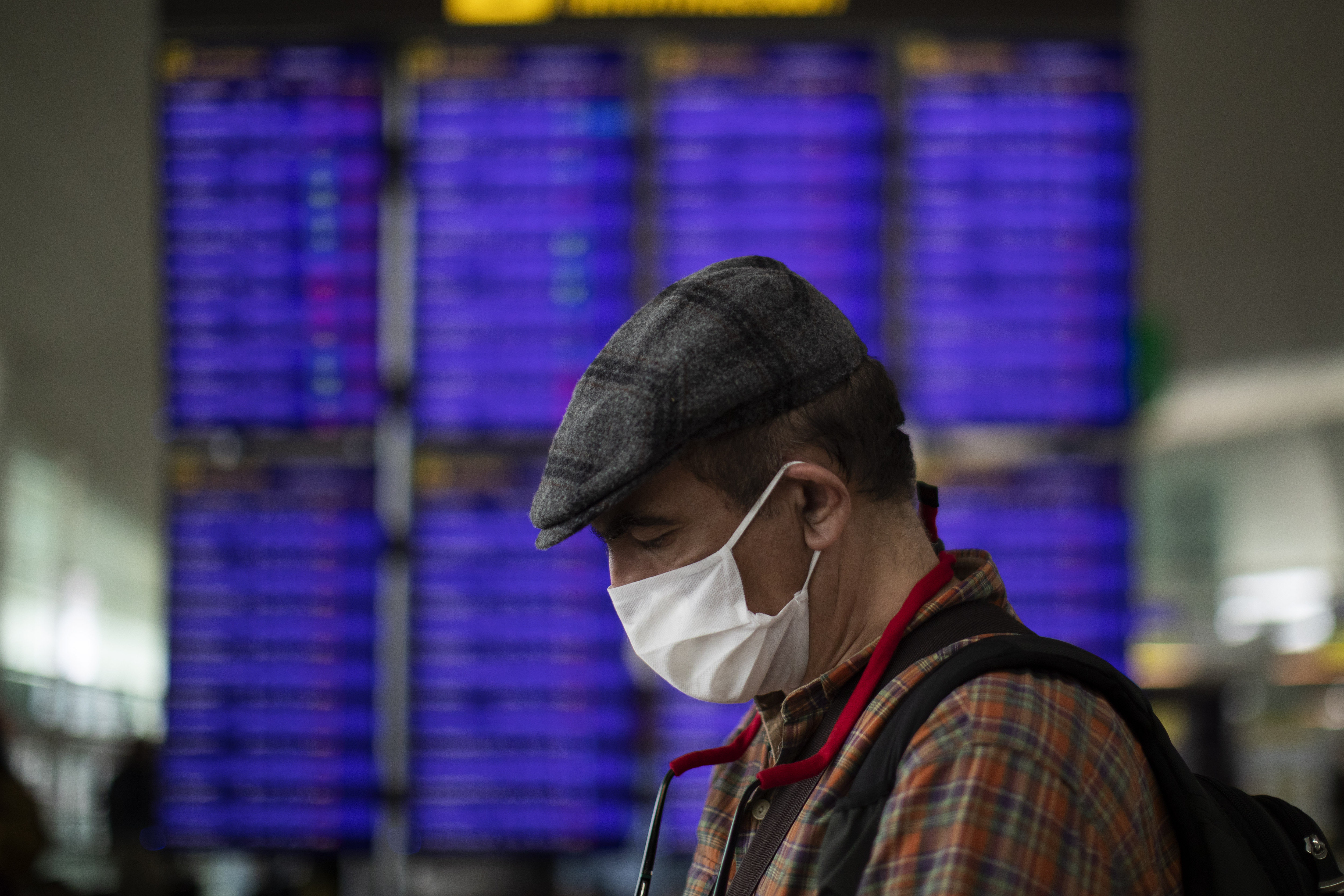 A man looks at his phone in front of the information screen at Barcelona airport, Spain, Thursday, March 12, 2020. President Donald Trump, who had downplayed the coronavirus for weeks, suddenly struck a different tone, announcing strict rules on restricting travel from much of Europe to begin this weekend. For most people, the new coronavirus causes only mild or moderate symptoms, such as fever and cough. For some, especially older adults and people with existing health problems, it can cause more severe illness, including pneumonia. (AP Photo/Emilio Morenatti)