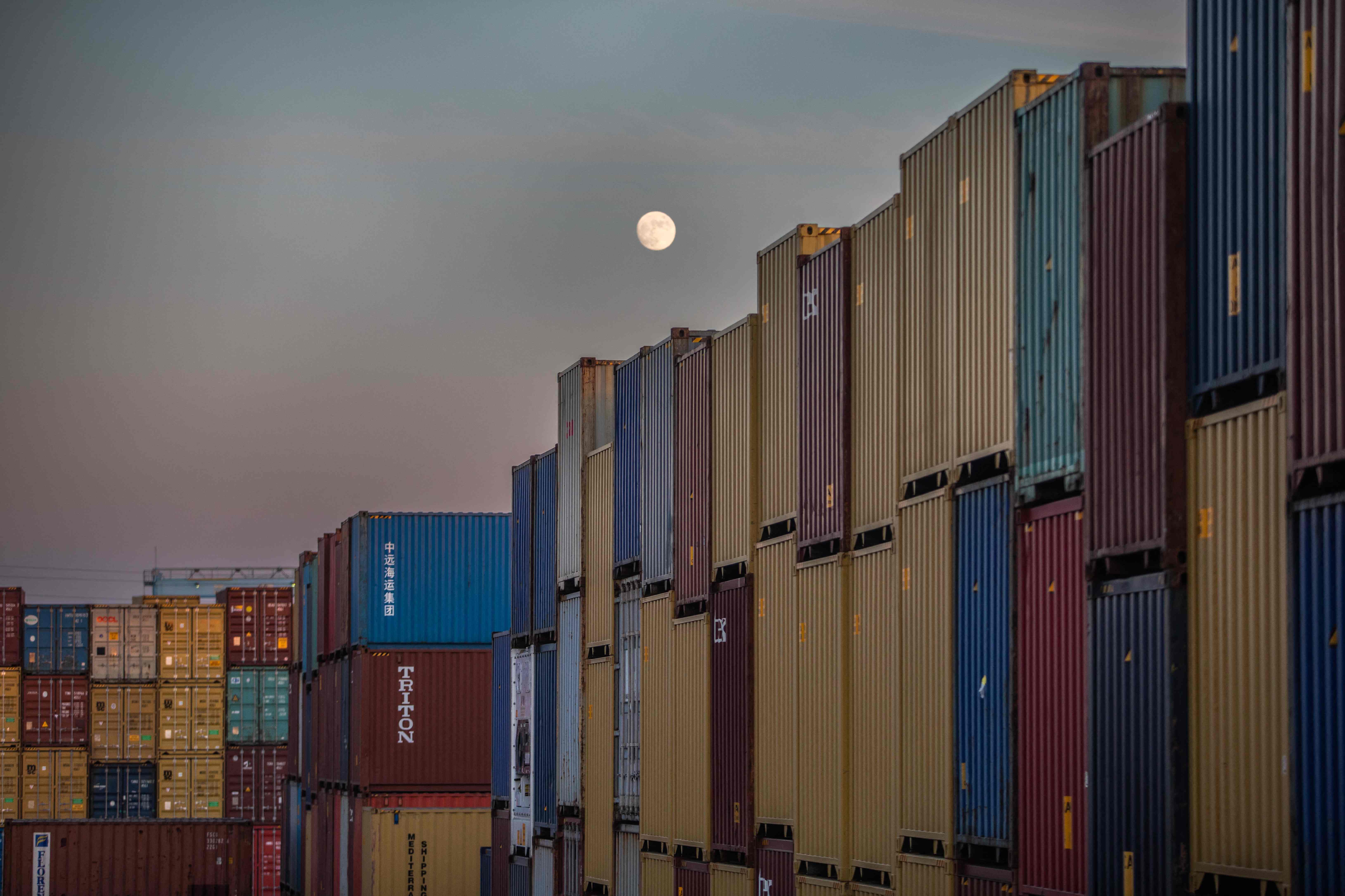 The moon is seen above shipping containers inside the Port of Los Angeles in San Pedro, California, November 17, 2021. - This morning the Governor of California, Gavin Newsom joined John Porcari, port envoy to the Biden administration's Supply Chain Disruptions TaskForce, legislators and local officials in the Los Angeles Harbor area to highlight the ongoing state and federal efforts to address port congestion. Congestion at US ports has caused supply chain disruptions, driving up prices and leading to a growing shortage of goods. (Photo by Apu GOMES / AFP)