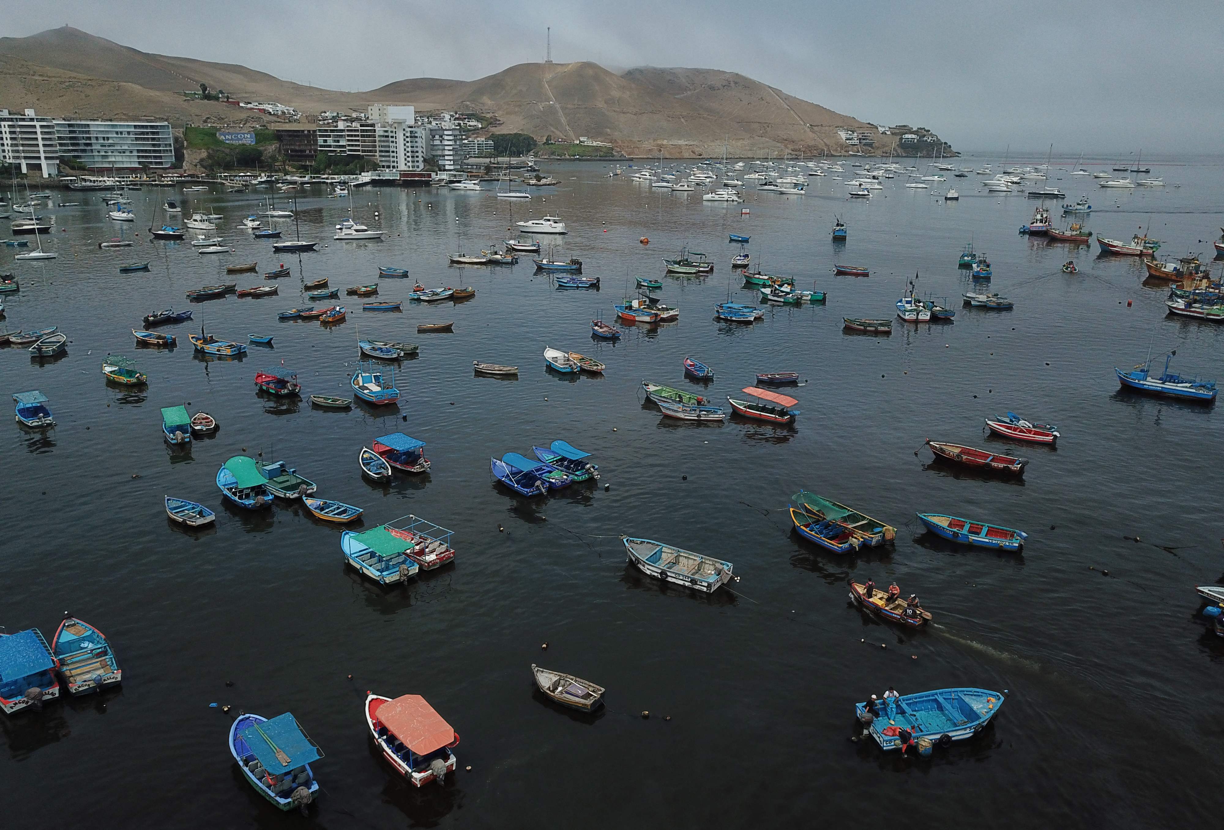 Aerial view of moored fishing boats, days after an oil spill that affected the resort town of Ancon, Peru, on January 21, 2022. - At Miramar Beach in Peru's popular resort of Ancon, there are no bathers despite the summer heat. Instead, it teems with workers in coveralls cleaning up an oil spill. Almost a million liters (264,000 gallons) of crude spilled into the sea on Saturday when a tanker was hit by waves while offloading at La Pampilla refinery in Ventanilla, 30 kilometers (19 miles) north of Lima. (Photo by Cris BOURONCLE / AFP)