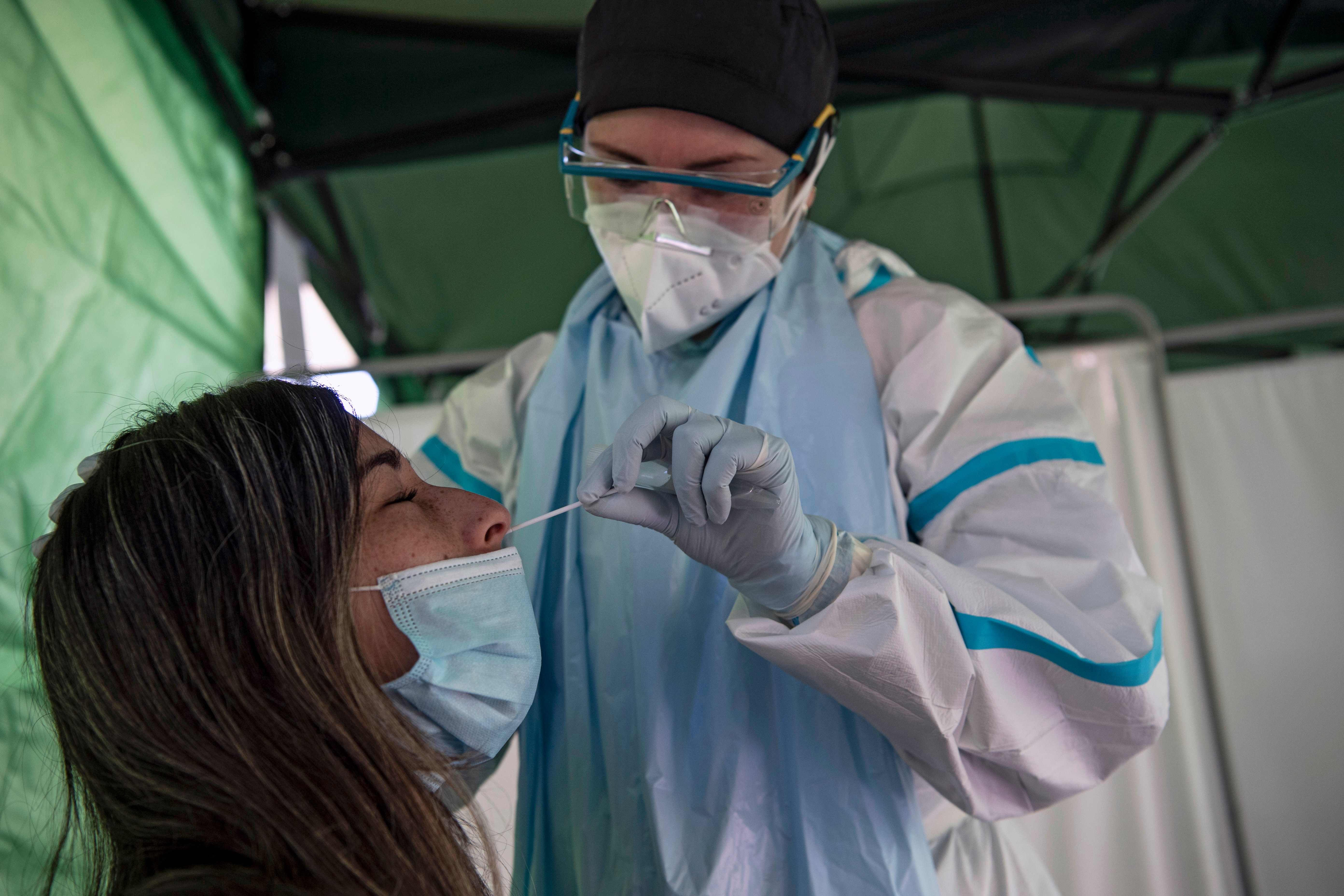 A woman undergoes a PCR test for the novel coronavirus at a control post in the municipality of Renca, Santiago on August 26, 2020. - After critical weeks in May and June, Chile managed to keep the new cases of coronavirus stable in most of the country. To avoid upsurges, it is now investing efforts to continue testing massively and to reinforce traceability, the key link to lift quarantines. (Photo by Martin BERNETTI / AFP)