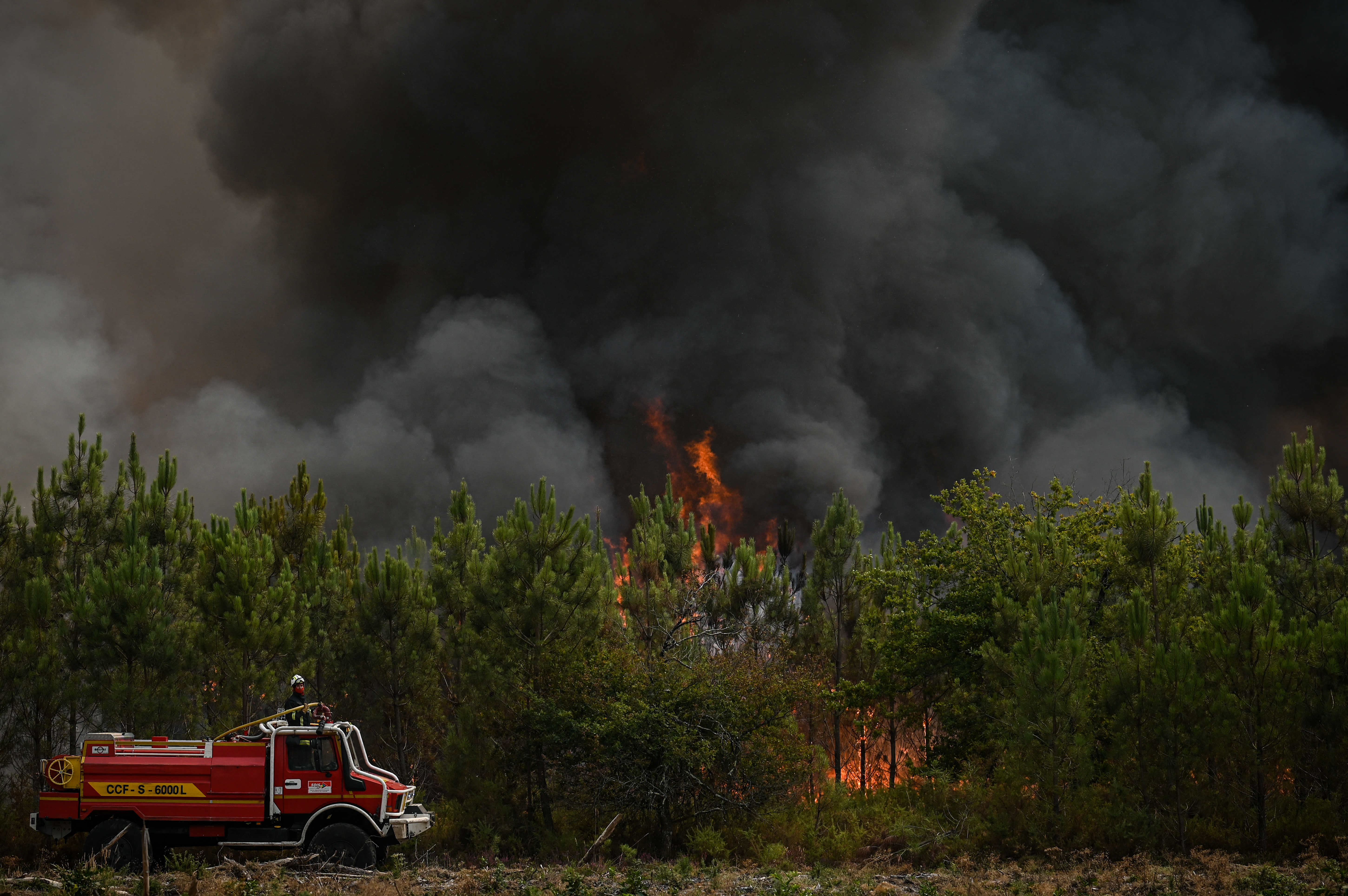 A firetruck drives close to the zone of a Pine tree blaze, near Saint-Magne, southwestern France on August 11, 2022. (Photo by Philippe LOPEZ / AFP)