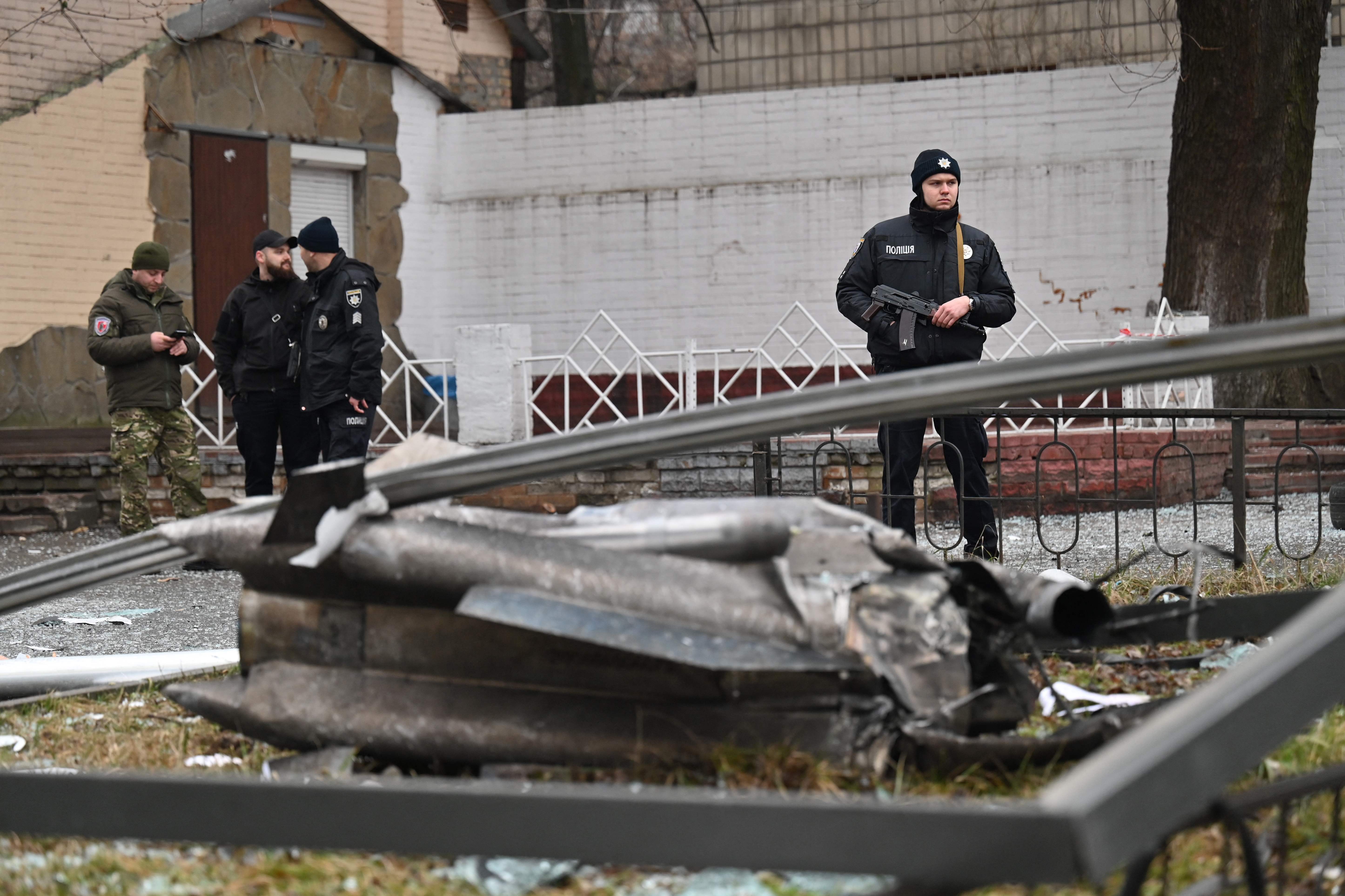 A police officer stands guard by the remains of a shell in Kyiv on February 24, 2022. - Russian President Vladimir Putin announced a military operation in Ukraine on Thursday with explosions heard soon after across the country and its foreign minister warning a "full-scale invasion" was underway. (Photo by Sergei SUPINSKY / AFP)