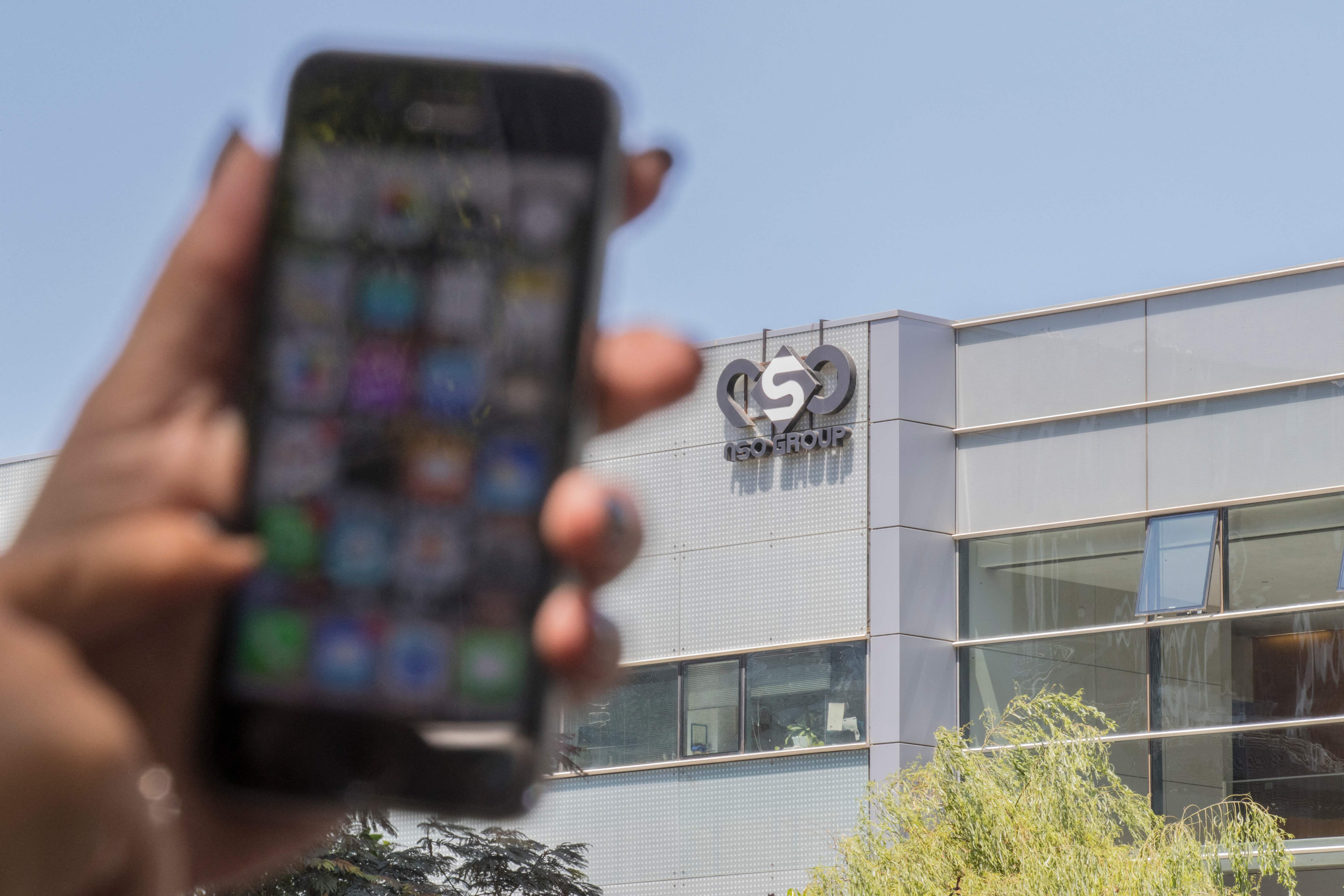 (FILES) In this file photo taken on August 28, 2016, a woman uses her iPhone in front of the building housing the Israeli NSO group "Pegasus", in Herzliya, near Tel Aviv. - An Israeli firm accused of supplying spyware to governments has been linked to a list of 50,000 smartphone numbers, including those of activists, journalists, business executives and politicians around the world, according to reports Sunday. (Photo by JACK GUEZ / AFP)