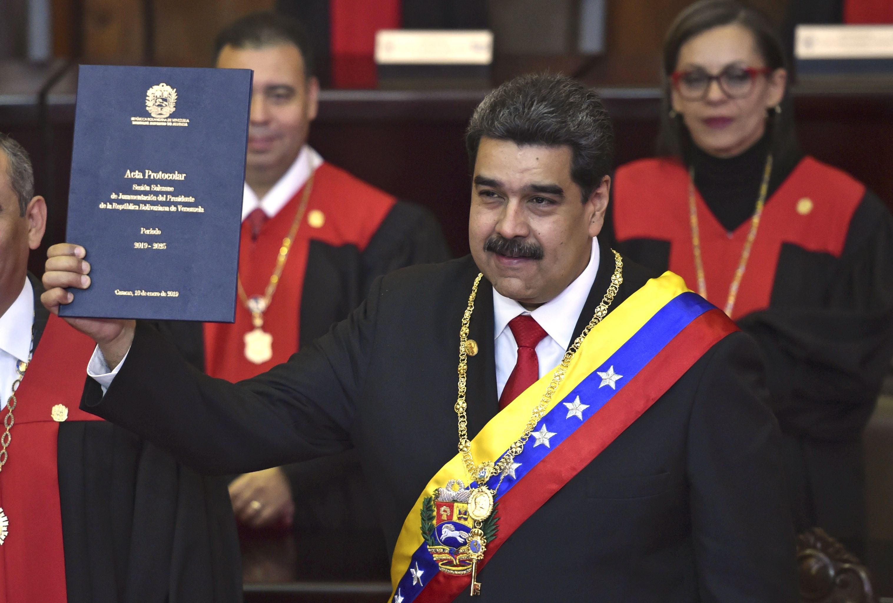 Venezuela's President Nicolas Maduro shows the inauguration ceremony protocol certificate at the TSJ headquarters in Caracas on January 10, 2019. - Maduro begins a new term that critics dismiss as illegitimate, with the economy in free fall and the country more isolated than ever. (Photo by YURI CORTEZ / AFP)