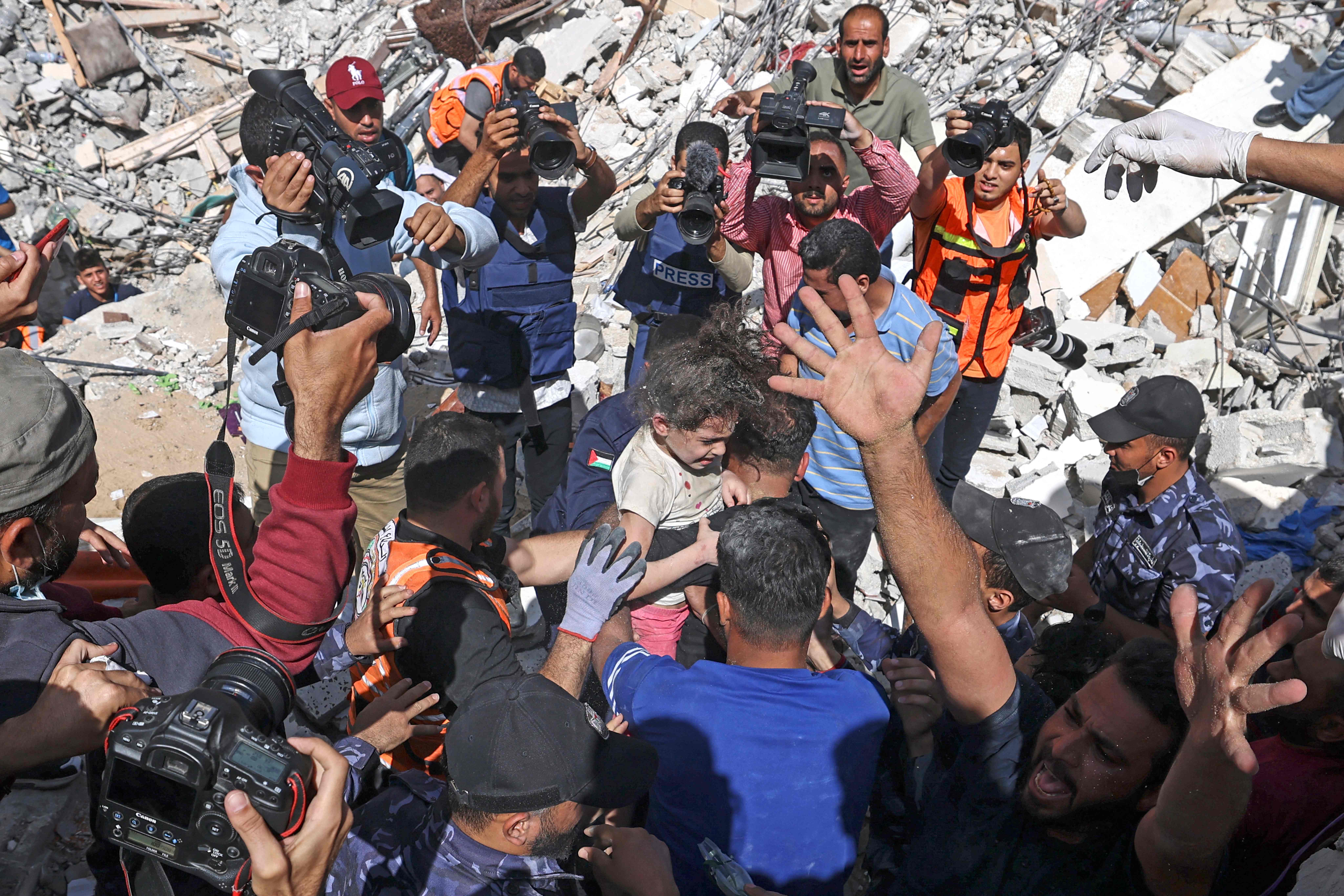Palestinians recover a girl from the rubble of a destroyed building in Gaza City's Rimal residential district on May 16, 2021, following massive Israeli bombardment on the Hamas-controlled enclave. - Israel's army said it had bombed the home of the political leader of Islamist group Hamas in the Gaza Strip, as the UN Security Council was to meet amid global alarm about the escalating conflict. (Photo by MAHMUD HAMS / AFP)