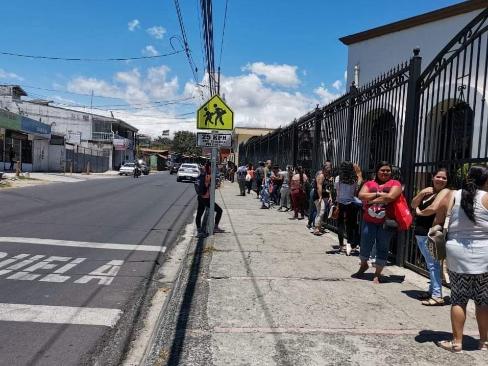 Oficiales de policía tuvieron que plantarse en la entrada de la institución alrededor de las 4 p. m. para contener a las personas, quienes conformaban una extensa fila desde horas de la mañana para recibir los paquetes de comida. Foto: Gustavo Artavia