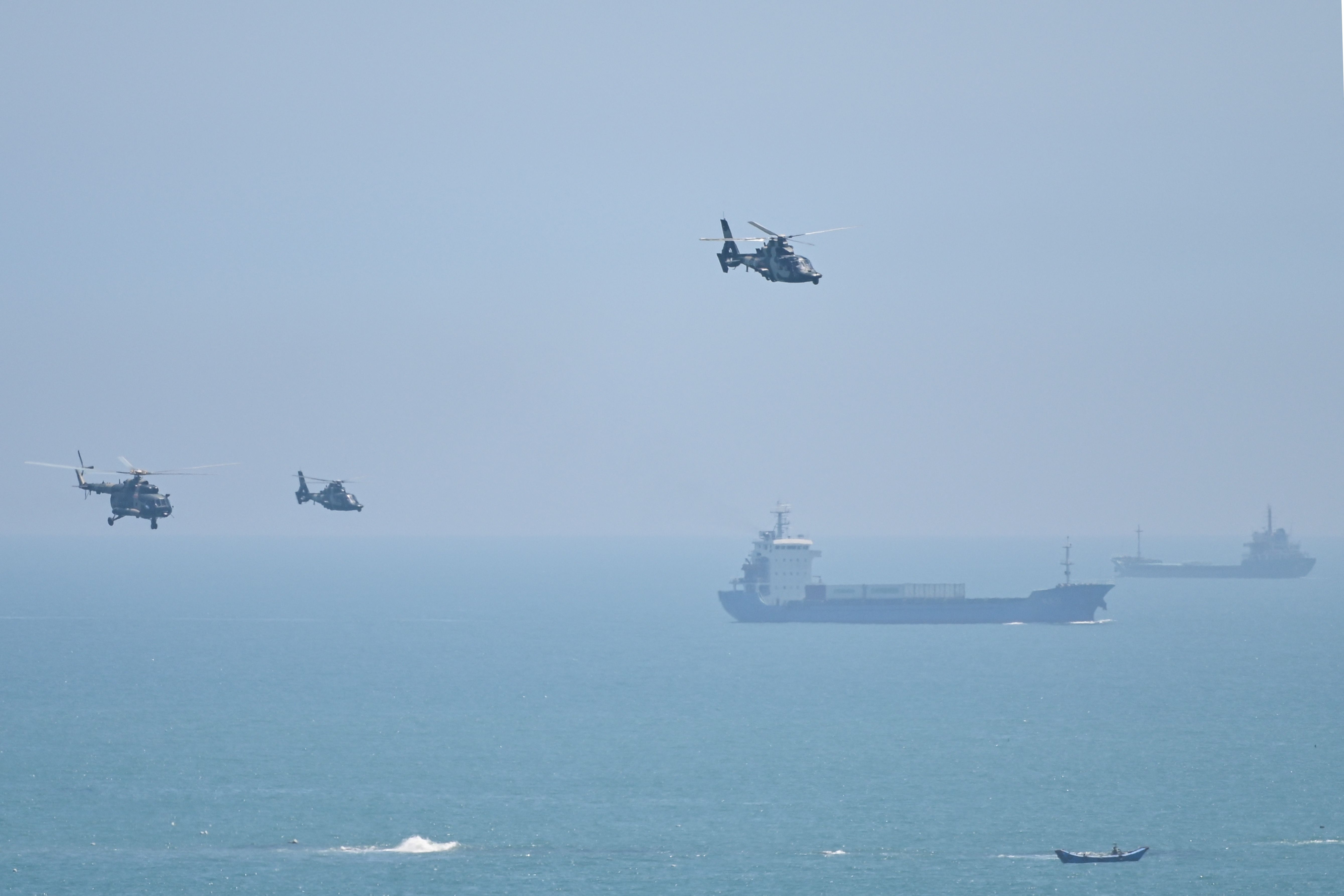 TOPSHOT - Chinese military helicopters fly past Pingtan island, one of mainland China's closest point from Taiwan, in Fujian province on August 4, 2022, ahead of massive military drills off Taiwan following US House Speaker Nancy Pelosi's visit to the self-ruled island. - China is due on August 4 to kick off its largest-ever military exercises encircling Taiwan, in a show of force straddling vital international shipping lanes following a visit to the self-ruled island by US House Speaker Nancy Pelosi. (Photo by Hector RETAMAL / AFP)