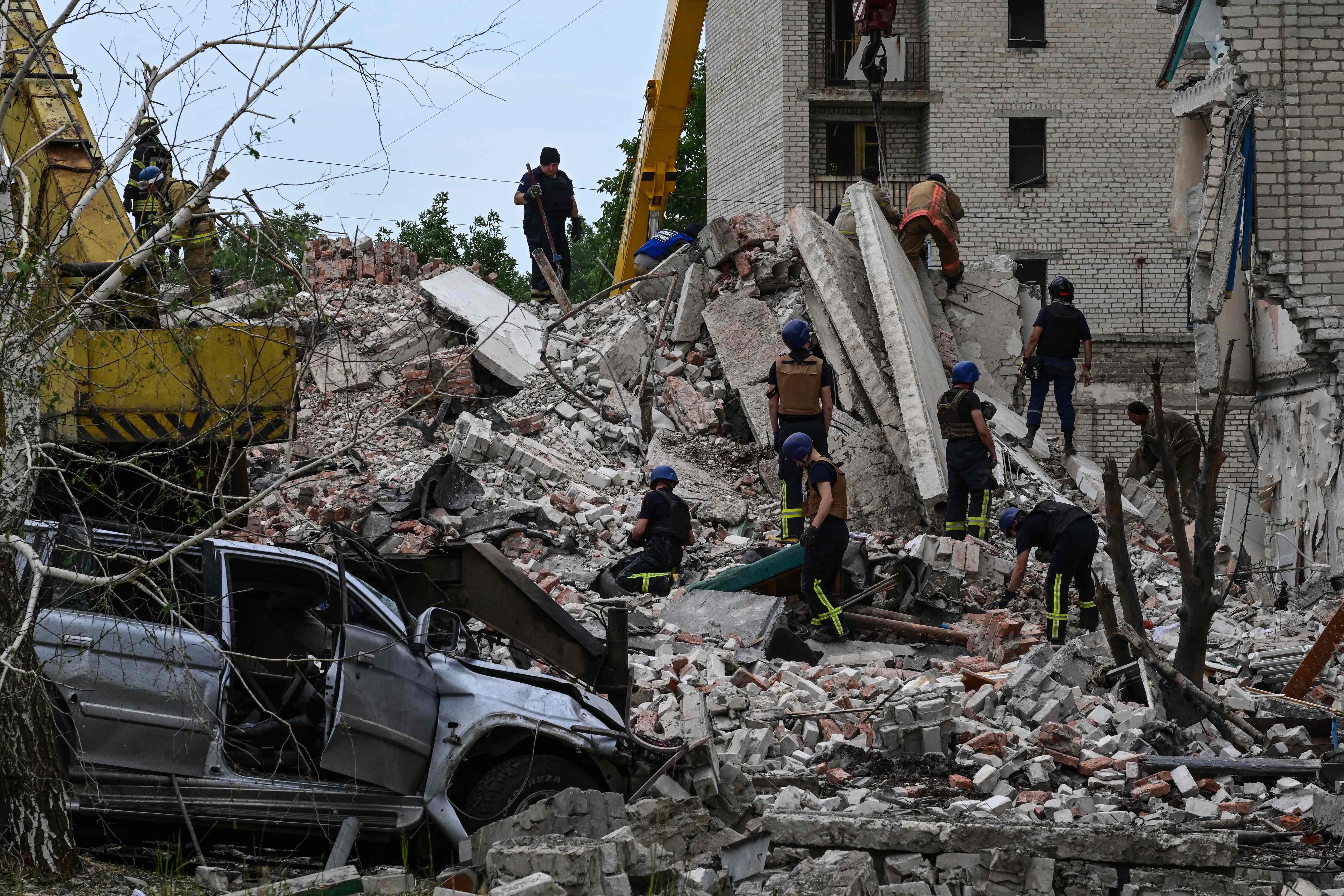 TOPSHOT - Rescuers clear the scene after a building was partialy destroyed as a result of Russian missile hit on a four-storey residential building in Chasiv Yar, Bakhmut District, eastern Ukraine, on July 10, 2022. - At least six people were killed and five others were injured in a Russian strike on an apartment building in Chasiv Yar town, a local official said. (Photo by MIGUEL MEDINA / AFP)